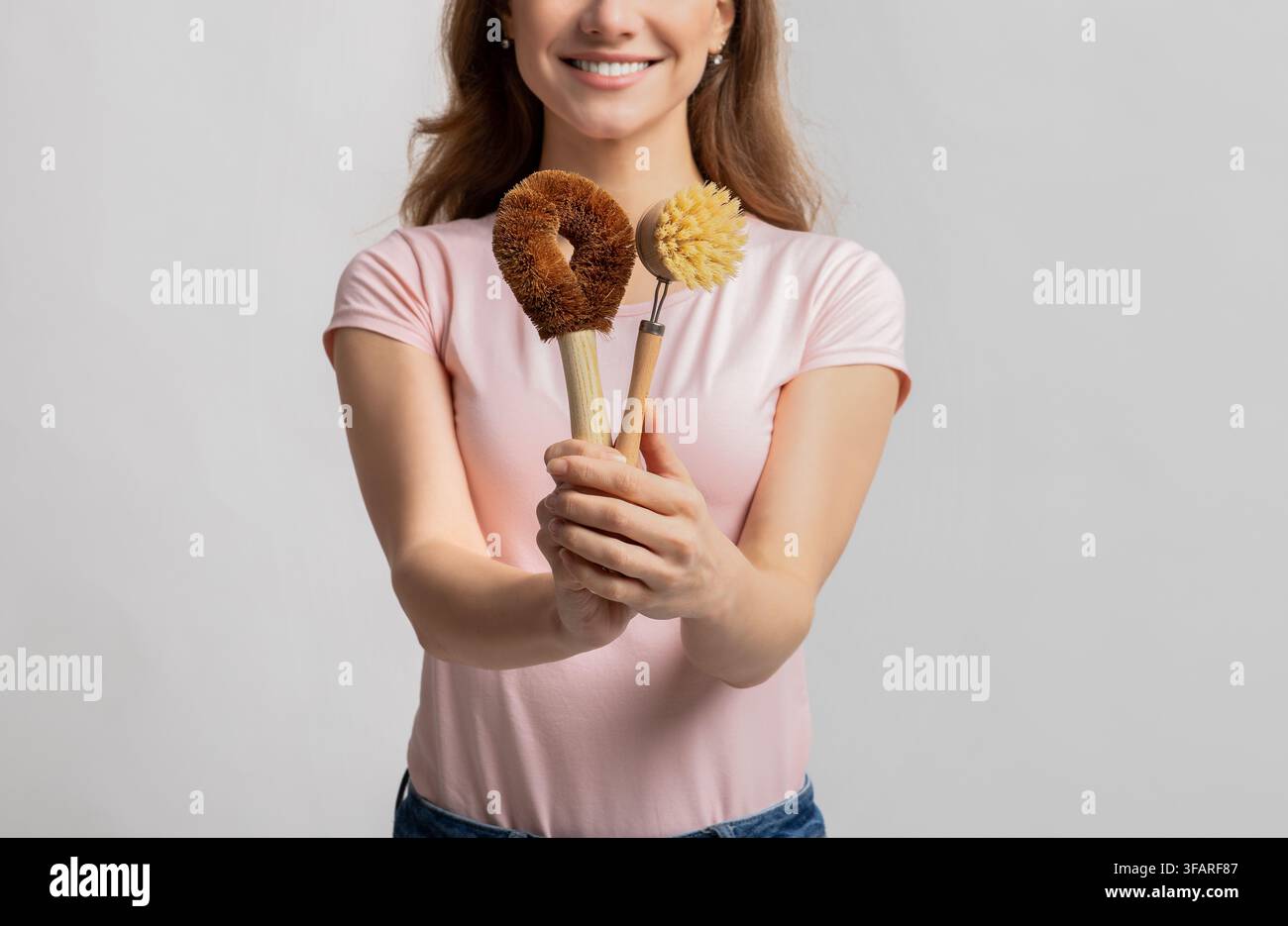 Lächelnde Frau hält drei umweltfreundliche Bürsten, Küche, nachhaltiges Reinigungskonzept Stockfoto
