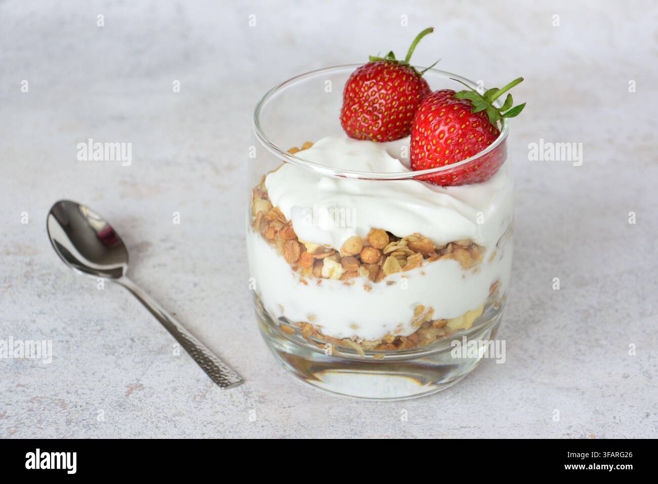 Gesunder Joghurt-Parfait mit Müsli und frischen Erdbeeren in einem Glas Stockfoto