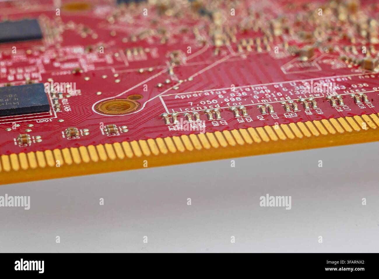 Rote Leiterplatte mit goldenen Steckern und elektronischen Komponenten. Teil einer Computerplatine auf grauem Hintergrund. Stockfoto