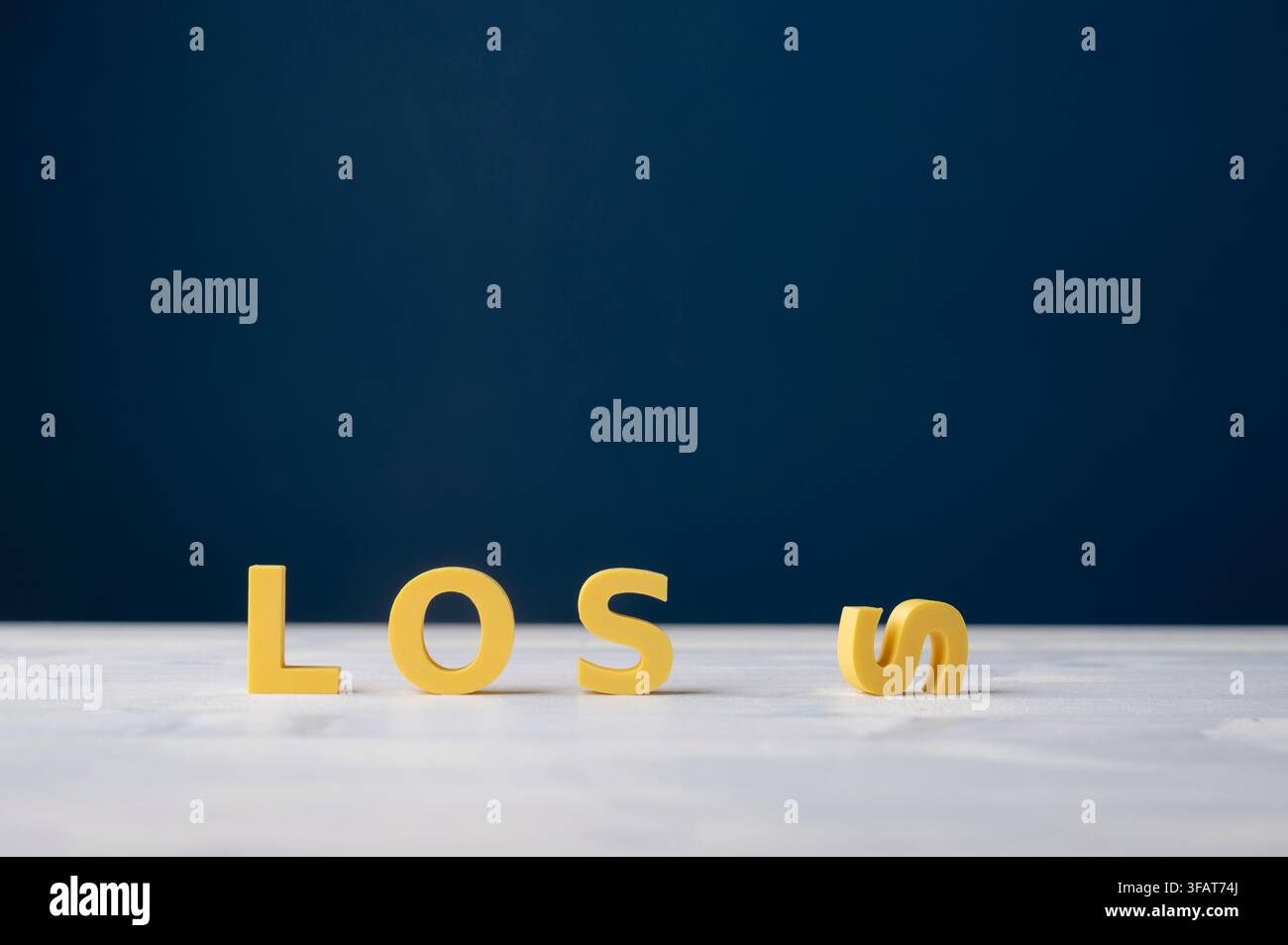Konzeptionelle Darstellung von gelben LOSS-Buchstaben, wobei der letzte Buchstabe seitlich umgefallen ist, vor einem dunkelblauen Hintergrund. Symbol für Verlust, Scheitern, Rückschlag, Ende Stockfoto