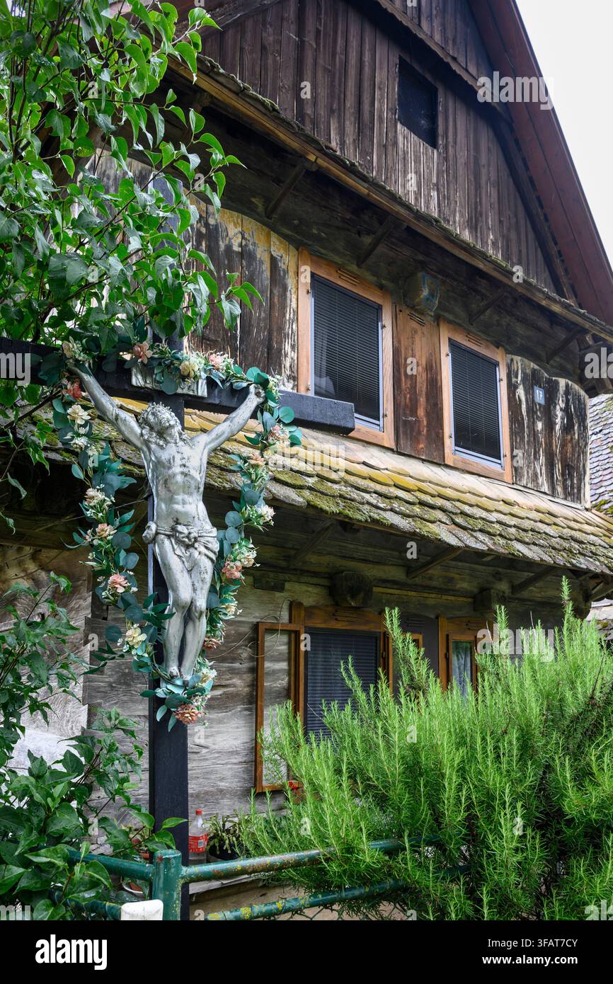 Ein Kruzifix im Vorgarten eines traditionellen Holzhauses im Dorf Cigoc. Lonjsko Polje Naturpark, Kroatien. Stockfoto