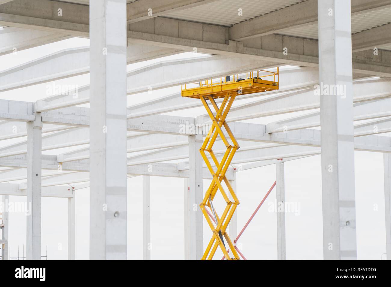 Erhöhte mobile Arbeitsbühne inspiziert Stahlbetonträger während der Entwicklung der Lagerinfrastruktur einer Industrieanlage Stockfoto