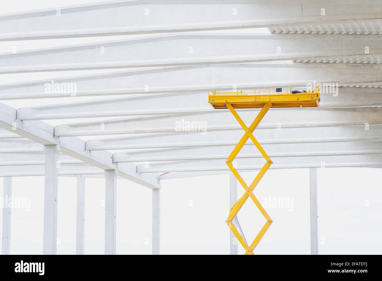 Mobile Hebebühne, die während der Installation des Deckenbereichs einer Industrieanlage unter vorgespannten Betonträgern positioniert ist Stockfoto
