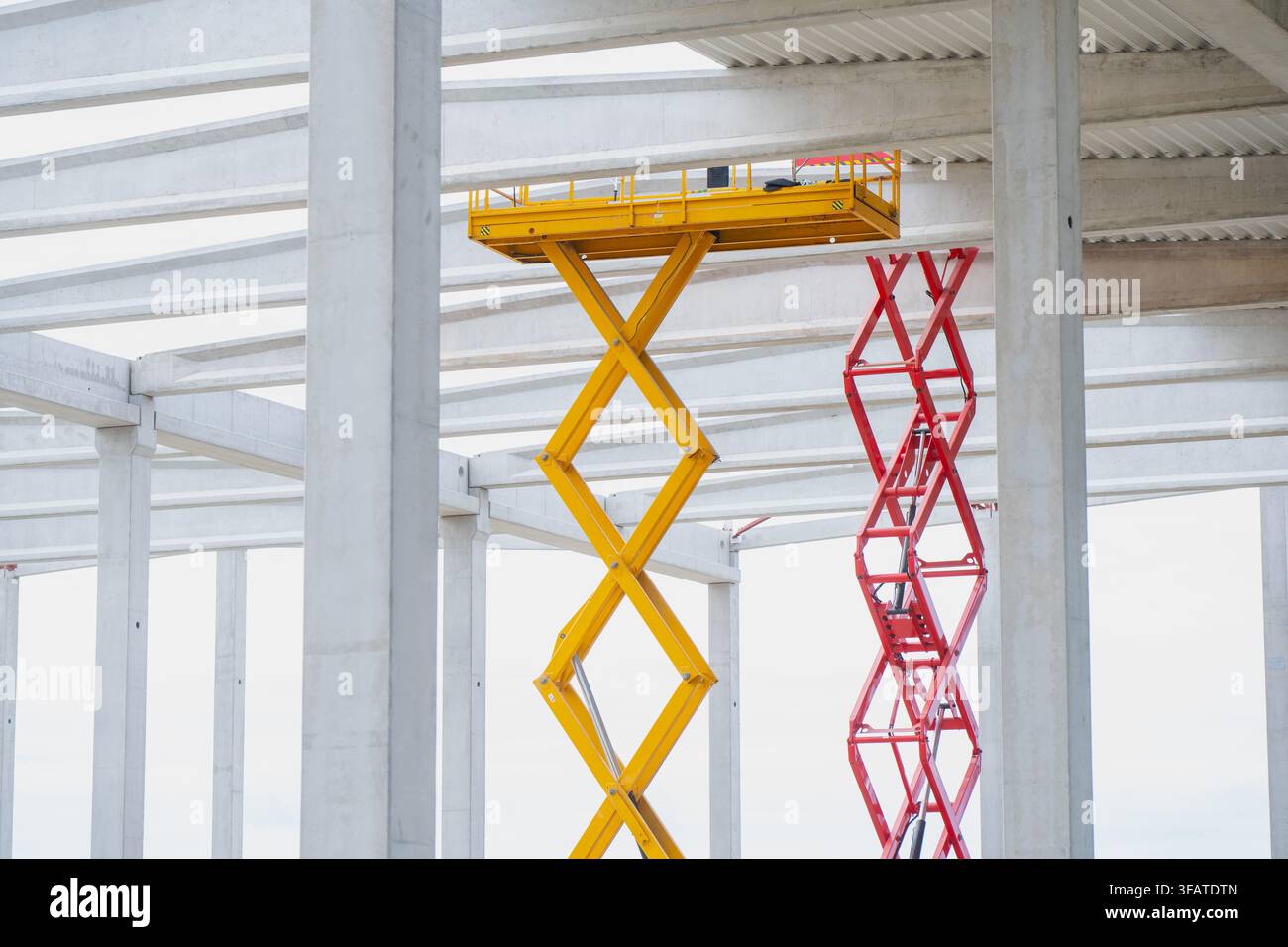 Mobile Hebebühnen, die während der Installation von Gewerbegebäuden unter strukturellen Betondachträgern arbeiten Stockfoto
