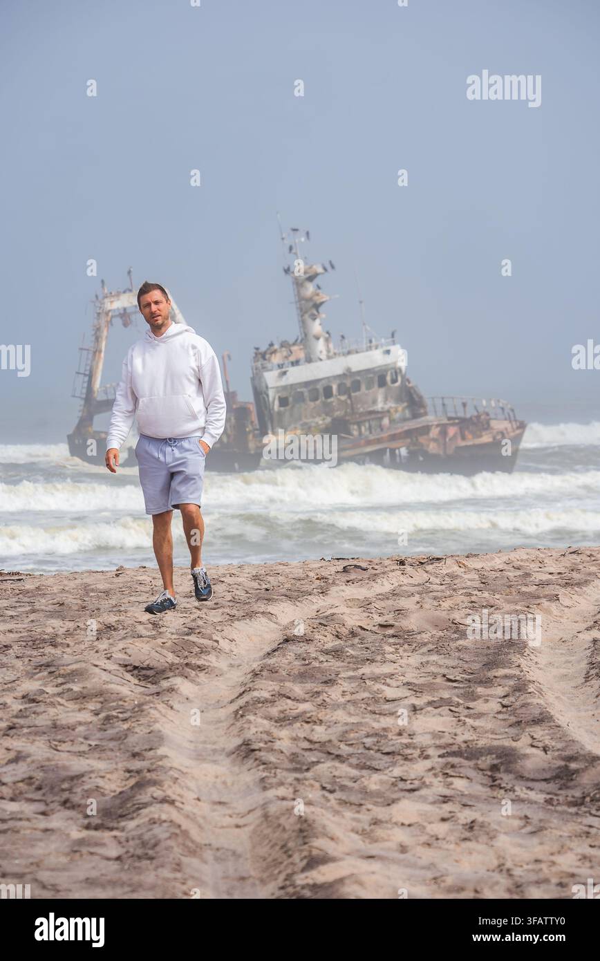 Mann läuft am Strand in der Nähe des Schiffswracks von Zeila in Namibia Stockfoto