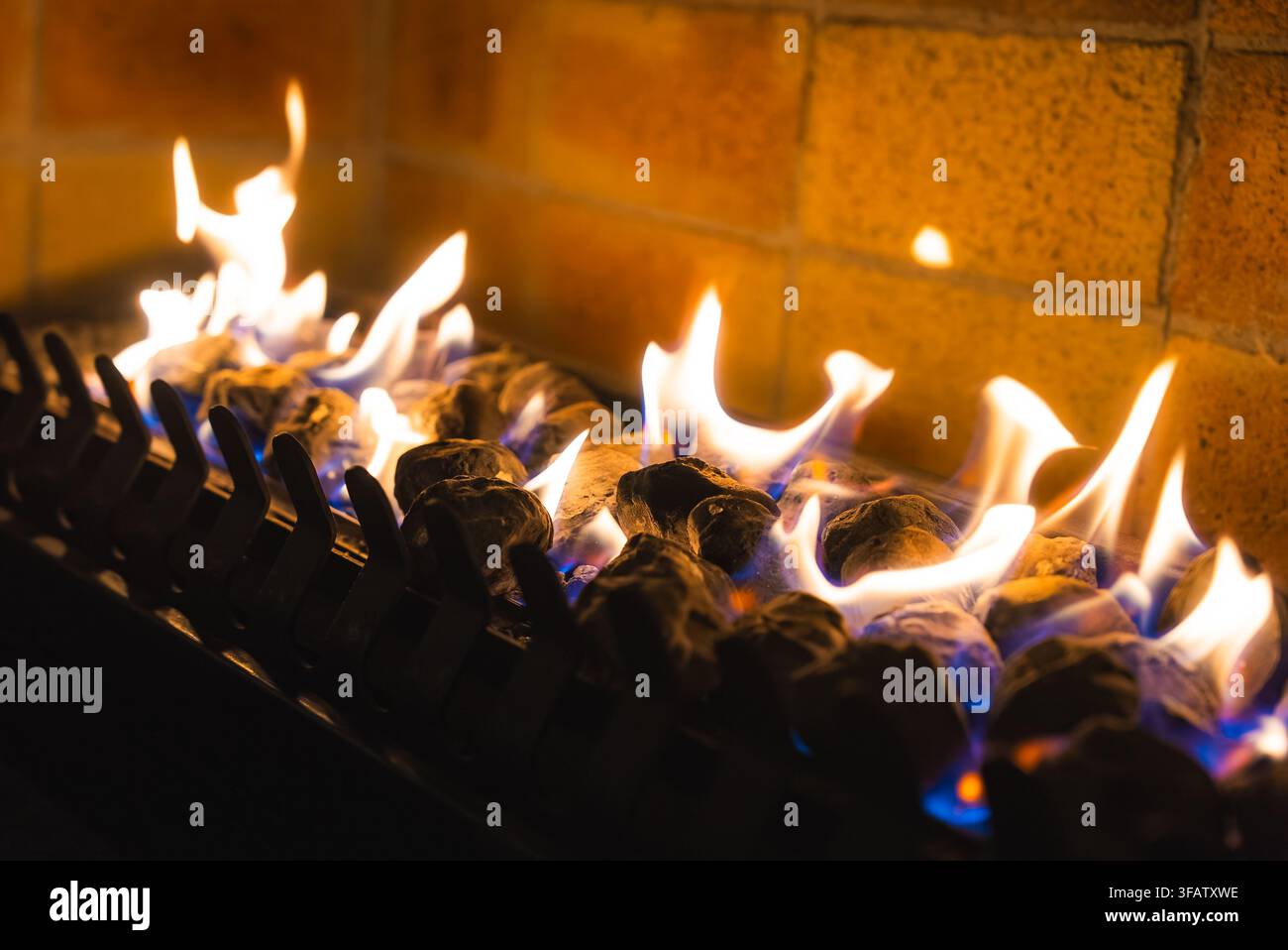 Flammen brennen über Kohle in einem modernen Kamin aus Ziegelstein Stockfoto