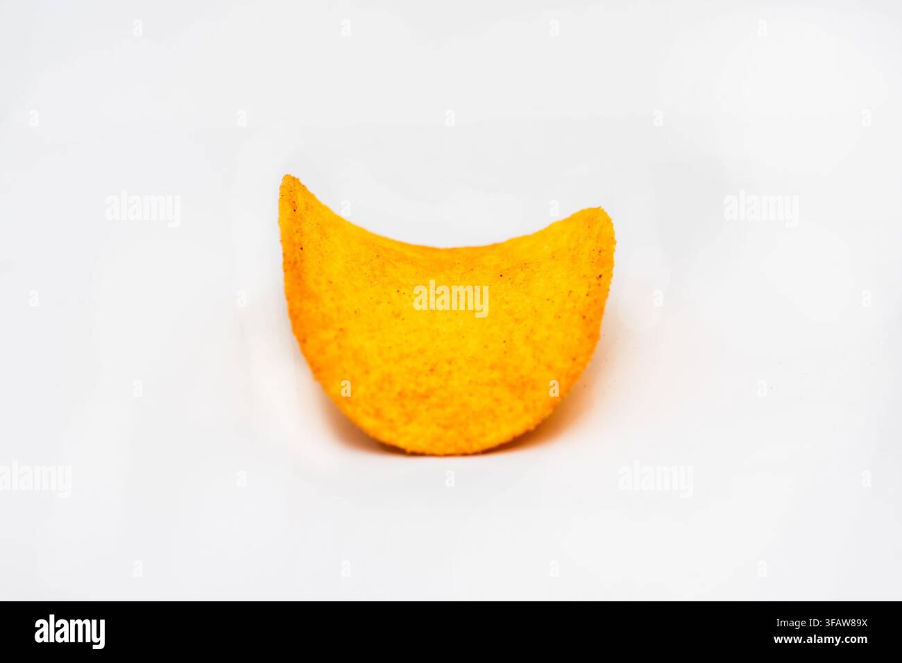 Eine einzelne gebogene Kartoffelchip ist auf einem sauberen weißen Hintergrund isoliert. Stockfoto