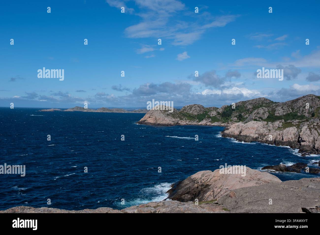 Dramatische norwegische Küste bei Lindesnes mit schroffen Granitfelsen, tiefblauem Meer und sonnigem Himmel, perfekt für Reise- und Naturinhalte. Stockfoto