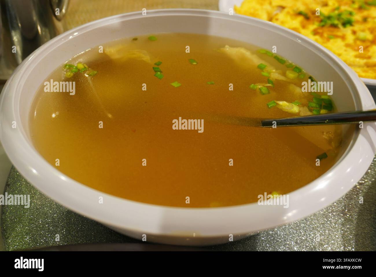 Helle klare Suppe mit grüner Zwiebel in weißer Schüssel Hausgemachte chinesische Suppe Stockfoto