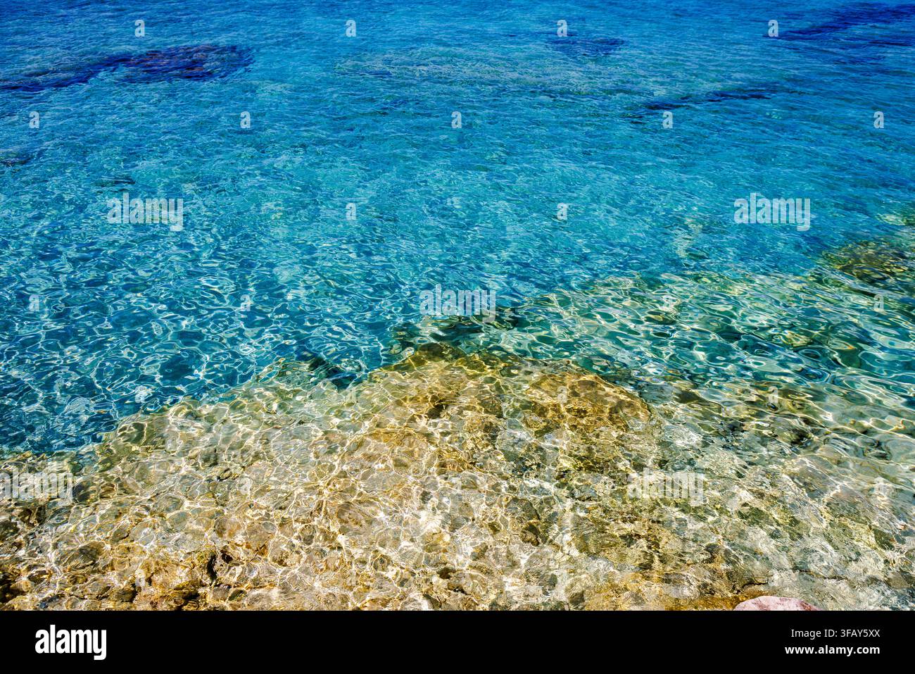 Transparantes türkisfarbenes Meerwasser, das über einen flachen, felsigen Meeresboden in Tropea, Italien, plätschert Stockfoto