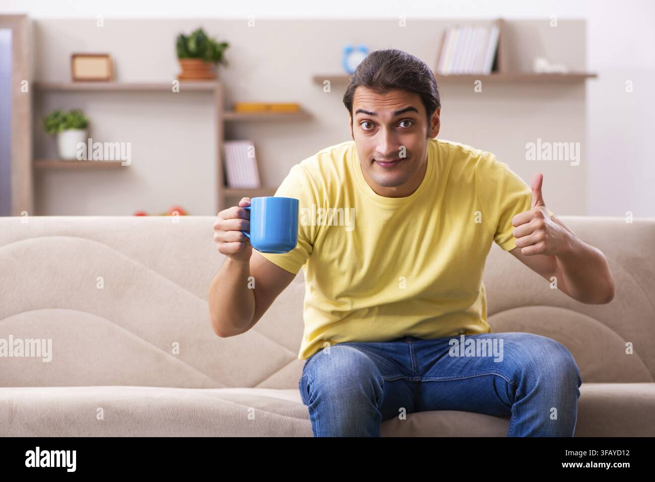 Junger Student trinkt Kaffee zu Hause Stockfoto