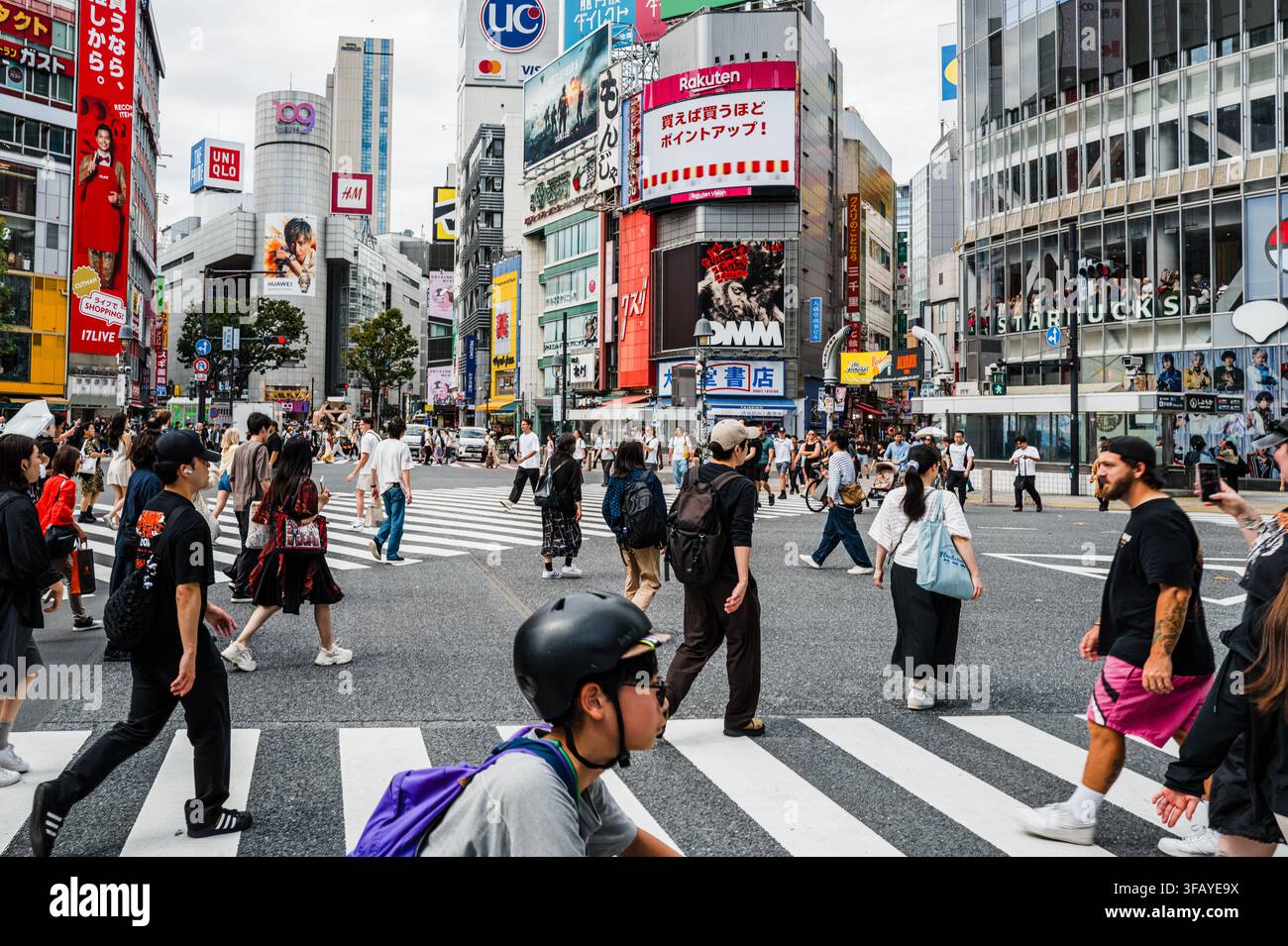 Menschenmassen überqueren den berühmten Shibuya-Kreuzungspunkt, umgeben von Werbung und Geschäften in Shibuya, Tokio, Japan. Stockfoto