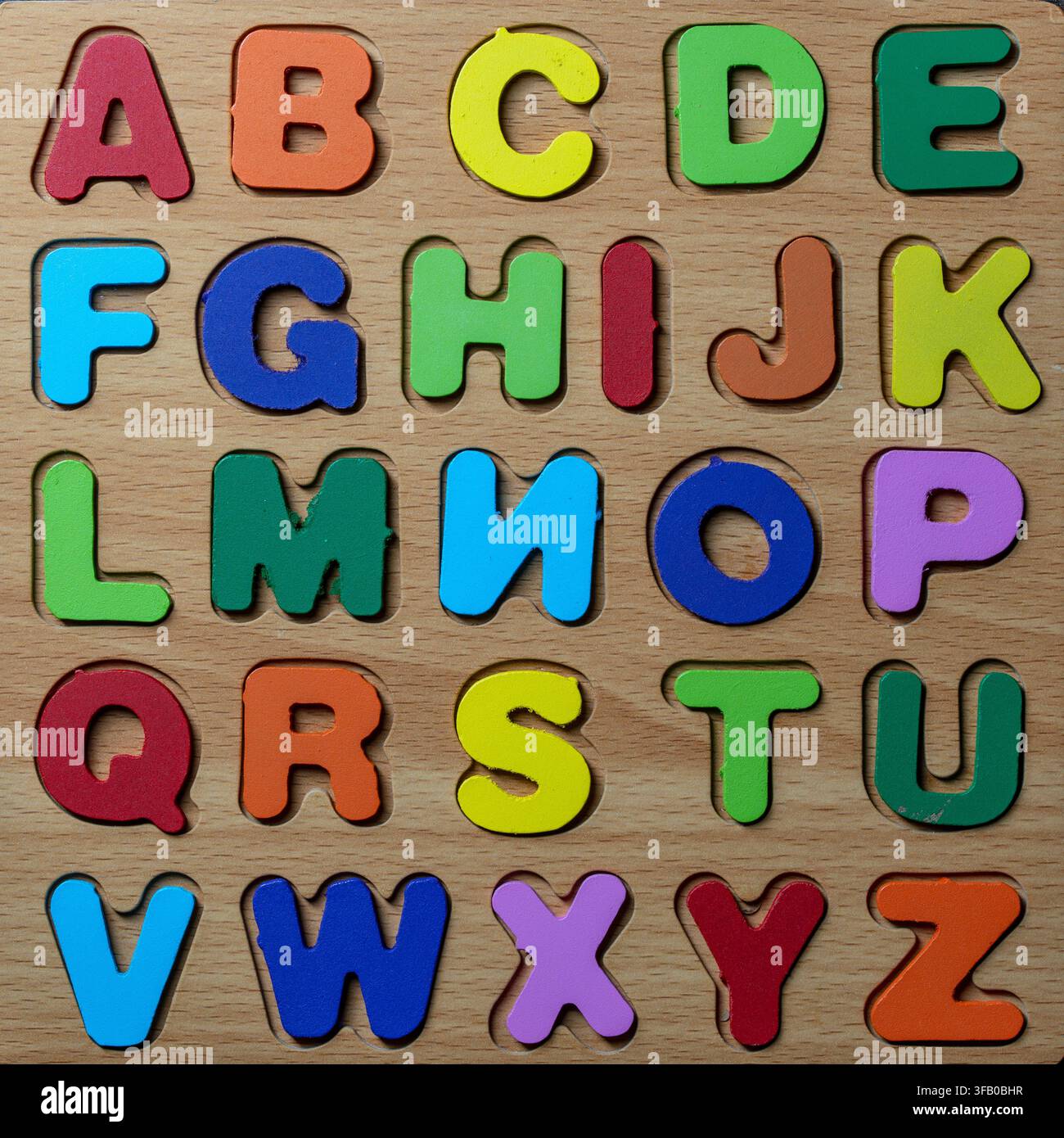 Farbenfrohes hölzernes englisches Alphabet-Puzzle-Spielzeug. Oberansicht eines pädagogischen hölzernen Alphabet-Brettpuzzles für Kinder mit mehrfarbigen Buchstaben von A bis Z arrangiert Stockfoto