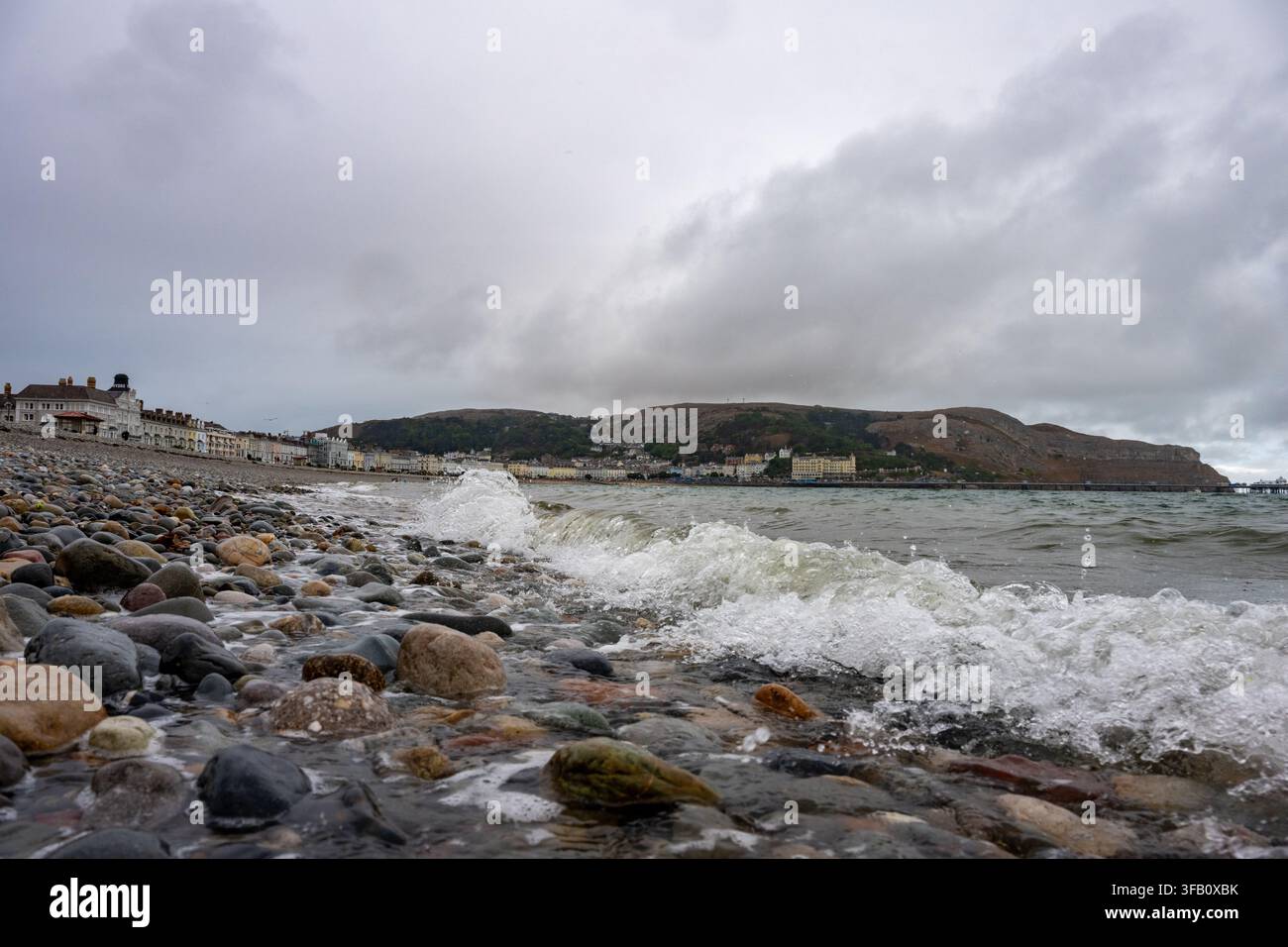Wellen, die über die Kieselsteine am Strand von Llandudno brechen Stockfoto