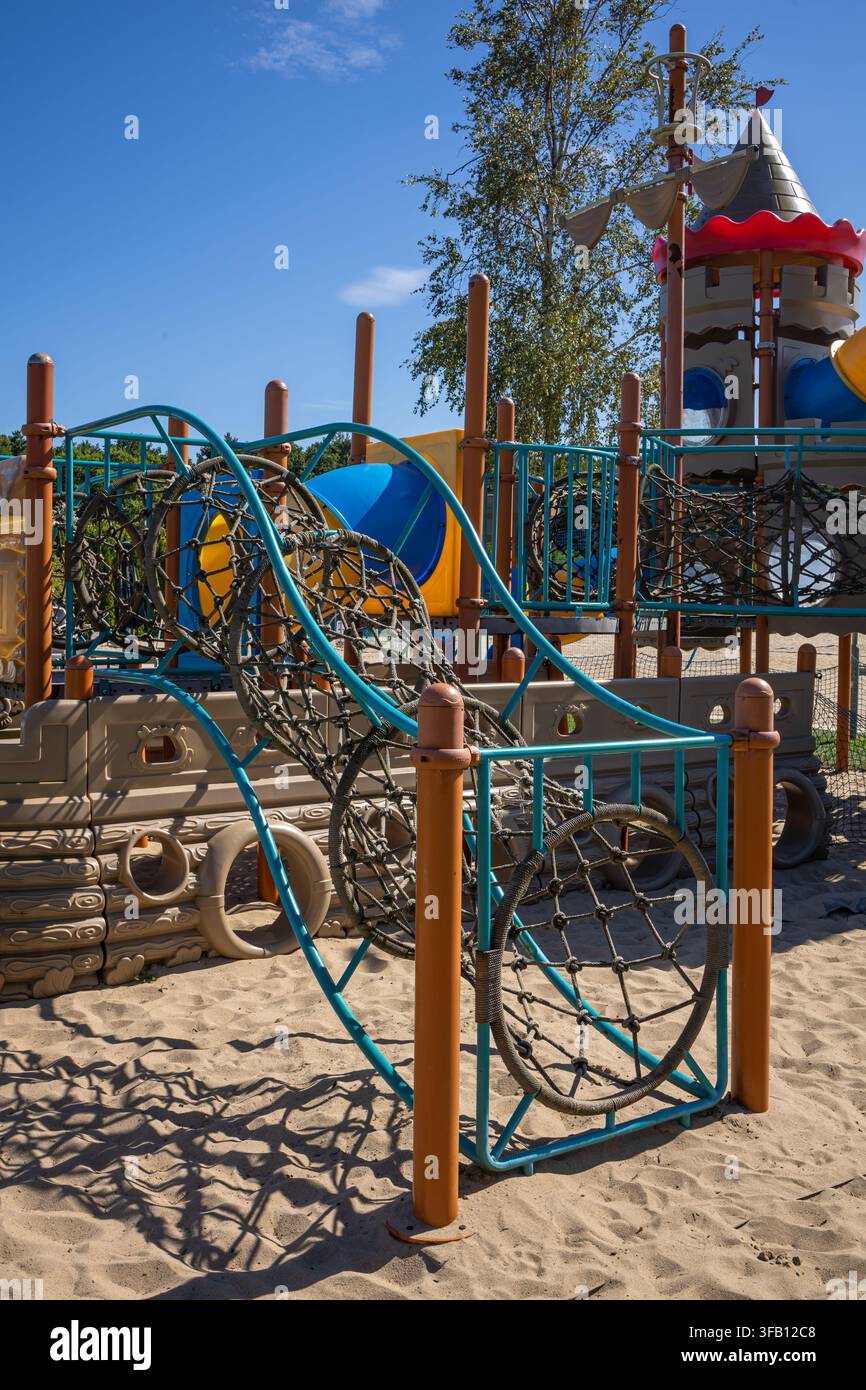 Farbenfroher Kinderspielplatzkomplex mit Rutschen, Türmen und Kletterseilen auf Sand im Erholungszentrum, Außenbereich für Kinderaktivitäten im Resort Stockfoto