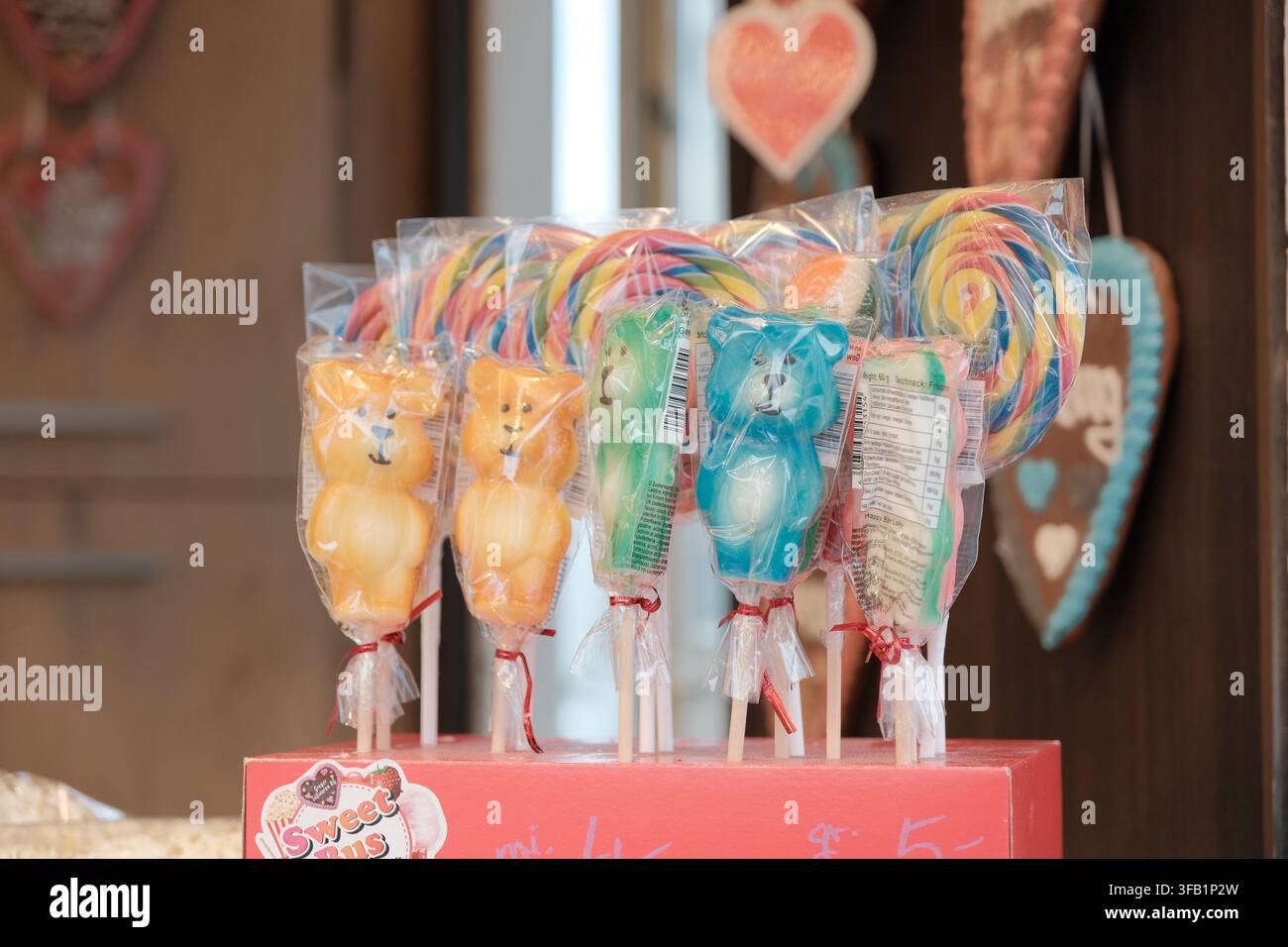 Auswahl an farbenfrohen süßen Leckereien, kandierten Früchten und Schokoladendesserts, die an einem traditionellen Jahrmarktstand präsentiert werden. Stockfoto