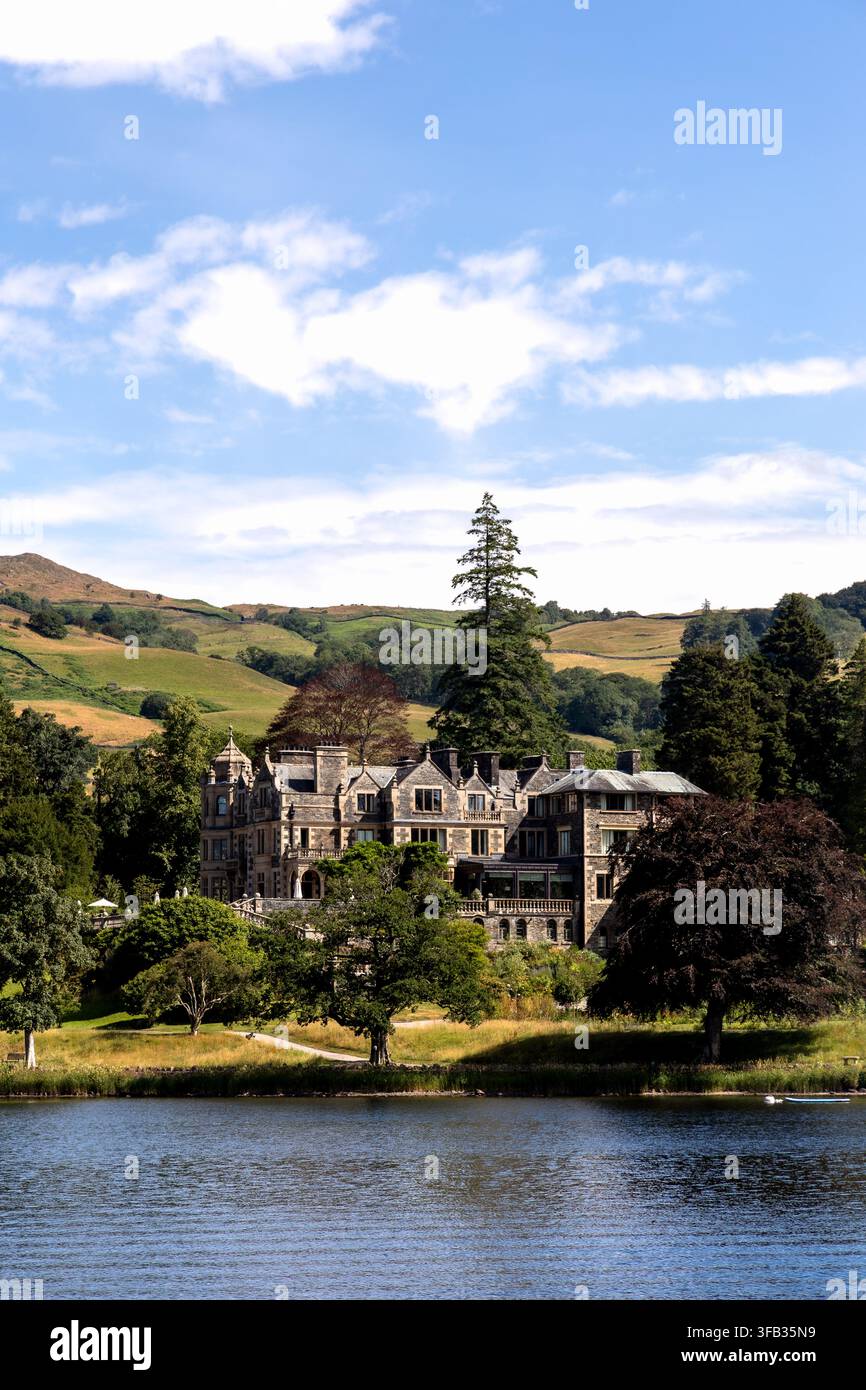 Lake Windermere, England, Vereinigtes Königreich - 19. Juli 2026: Großes historisches Anwesen am See, umgeben von alten Bäumen und sanften grünen Hügeln Stockfoto