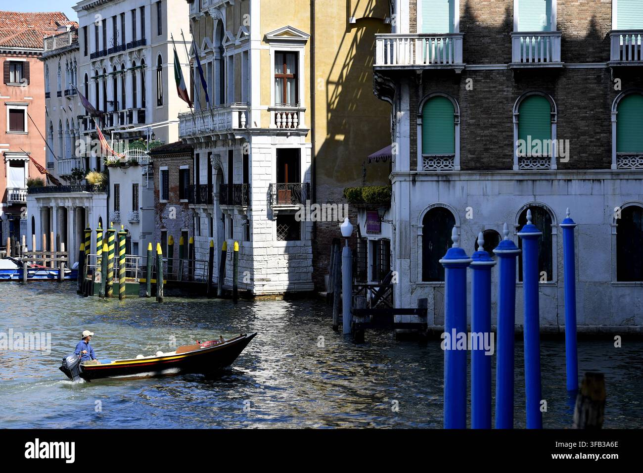 Ein Boot, das den historischen Canal Grande in Venedig, Italien, entlangfährt, vorbei an traditioneller Architektur und Anlegestellen. Stockfoto