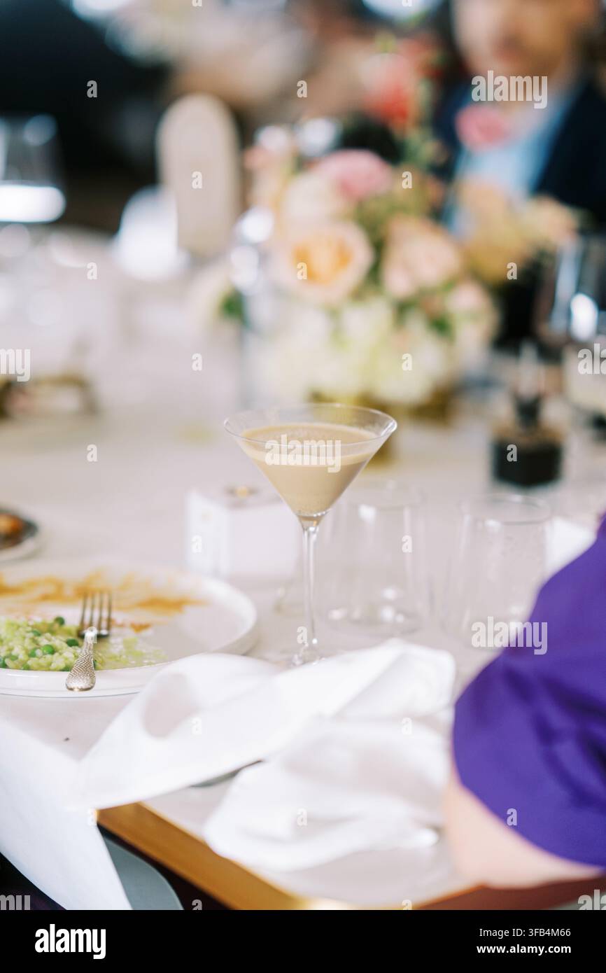 Elegante Tischgedeck mit Martiniglas und Blumenmitte bei einem Orchideen-Event Stockfoto