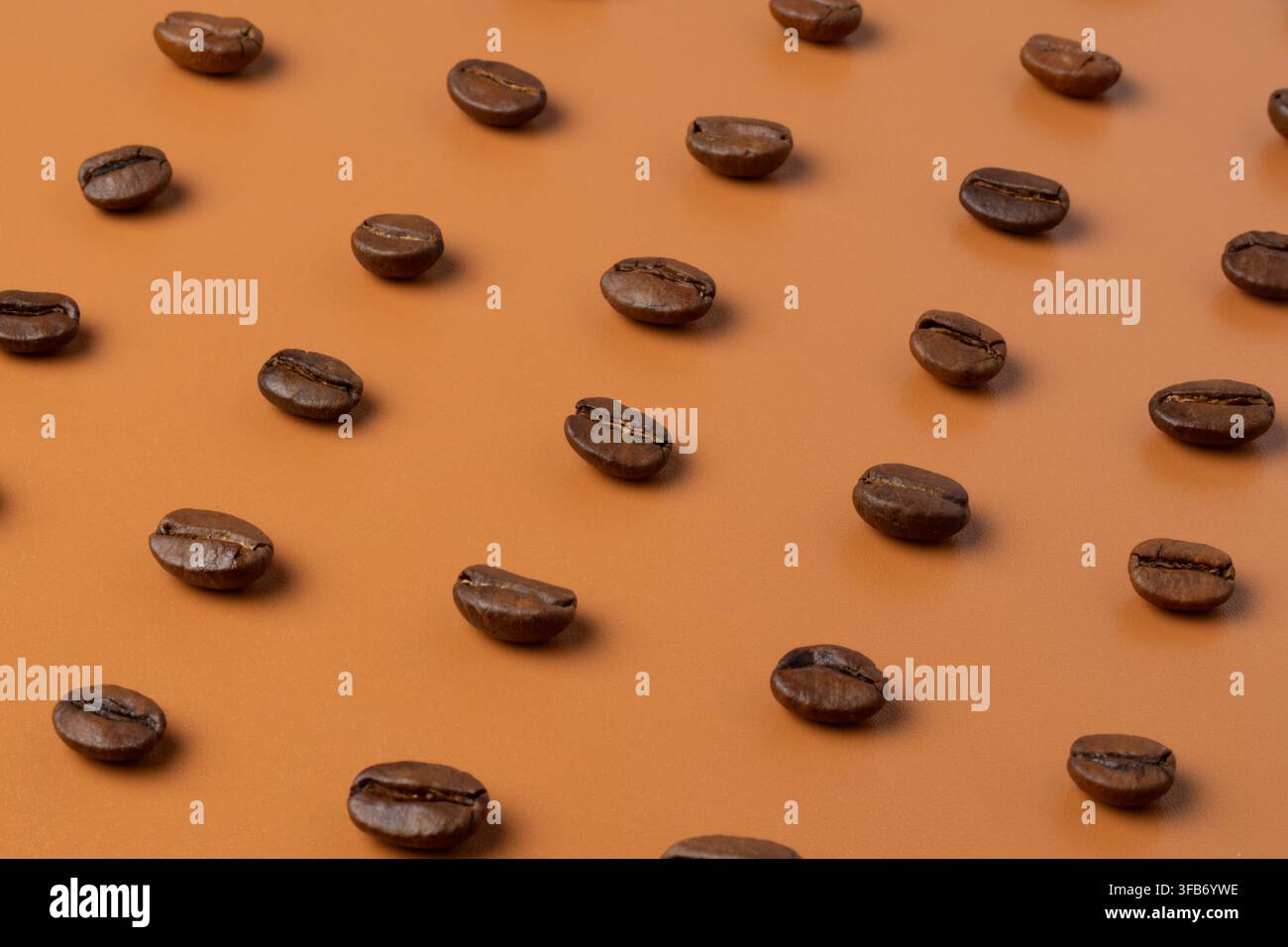 Schräge Makroaufnahme von gerösteten Kaffeebohnen, die in einem diagonalen geometrischen Raster angeordnet sind. Stockfoto