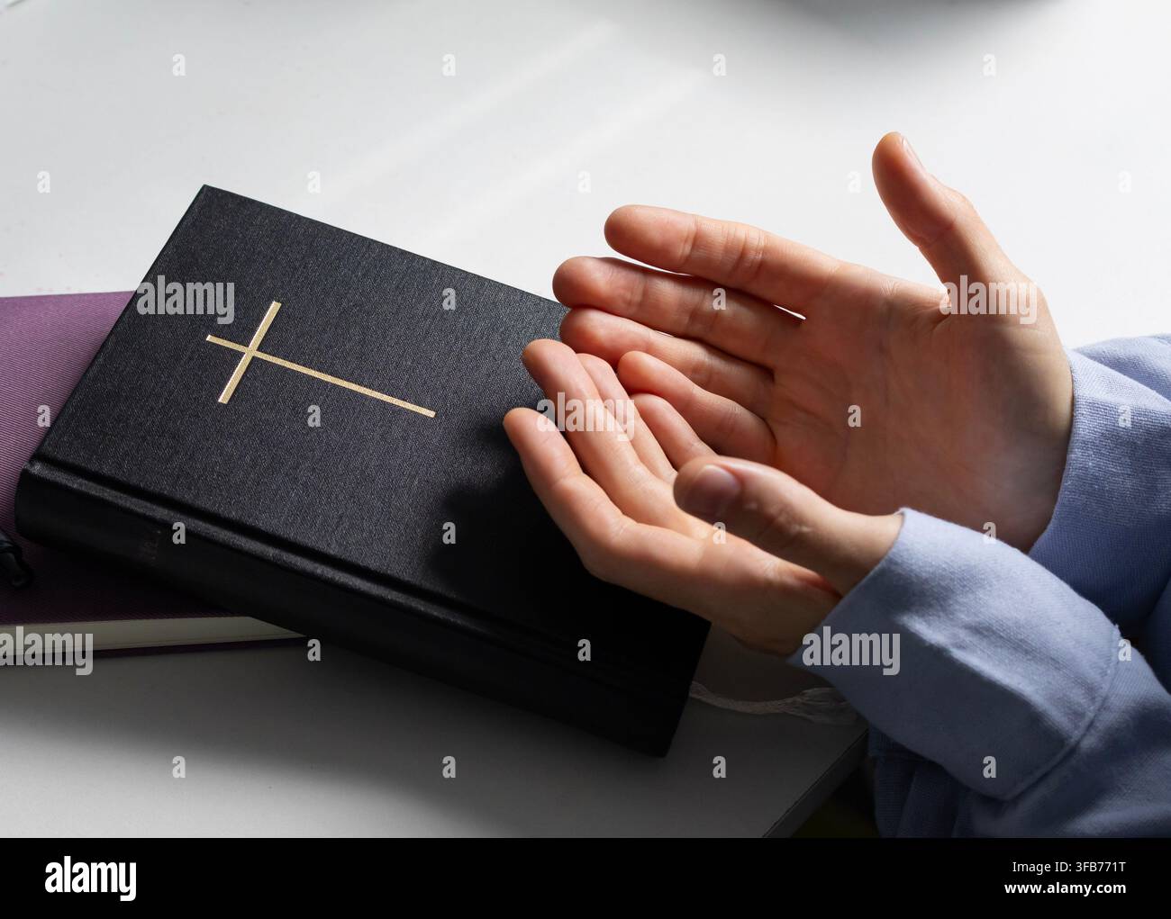 Christliche Frau betet mit offenen Händen neben der Heiligen Bibel Stockfoto