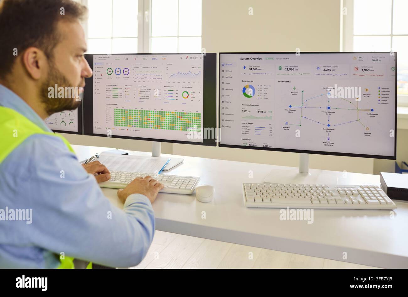 Ingenieur analysiert Daten auf zwei Computermonitoren im Industrie-Kontrollraum Stockfoto