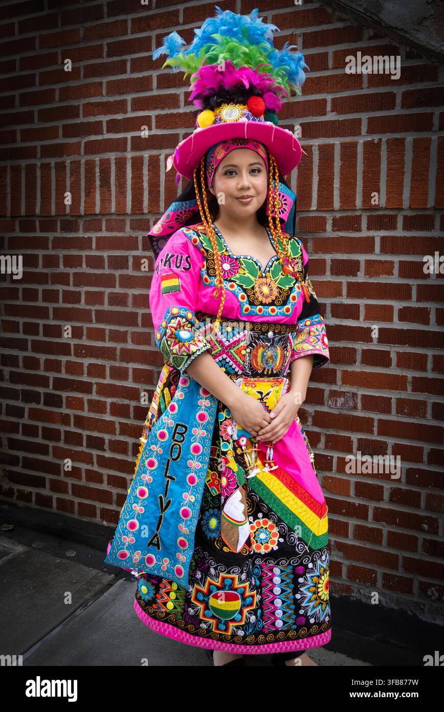 Eine sehr hübsche junge Dame in einem sehr aufwendigen farbenfrohen Kostüm vor dem Beginn der Bolivian Day Parade 2026 in Jackson Heights, Queens, New York. Stockfoto