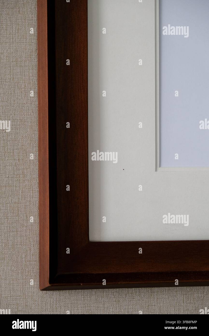 Nahaufnahme eines dunklen Holzbildrahmens mit weißem Passepartout an einer strukturierten Wand Stockfoto