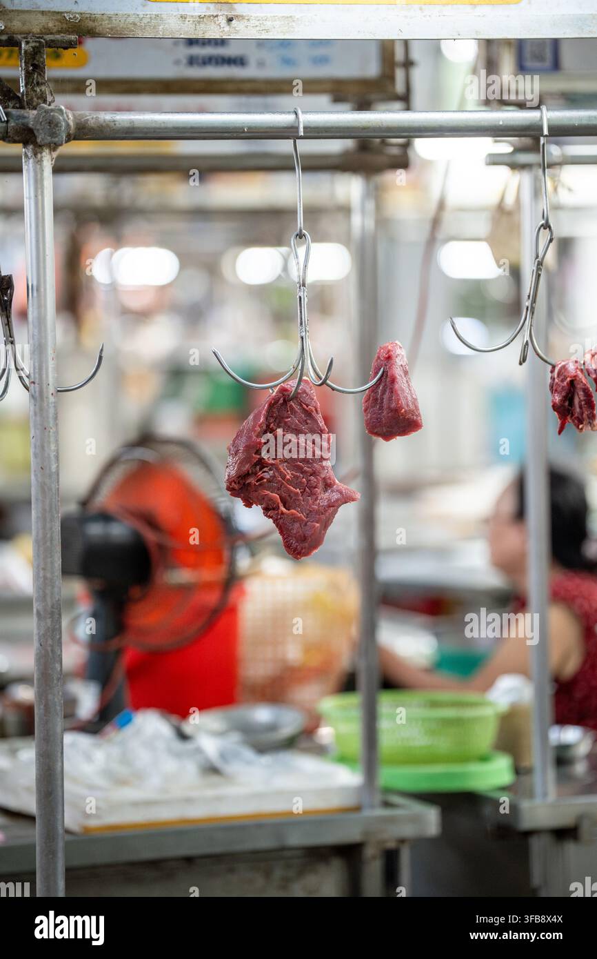Rohes Rind- oder Schweinefleisch, das an Metallhaken hängt und an einem Straßenimbissstand verkauft wird, Fleischgroßhandel. Stockfoto