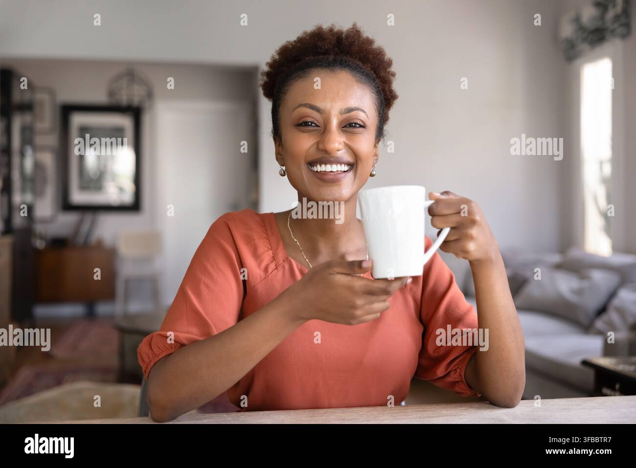 Glückliche Frau genießt ein heißes Getränk zu Hause Stockfoto