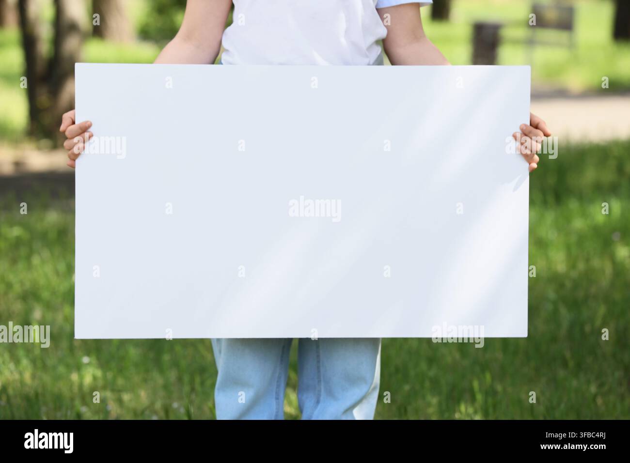 Protest und Aktivismus-Konzept, Kind hält leeres weißes Schild für Kopierfläche in einem Park, Umweltbewusstsein und Jugendadvokatie Stockfoto