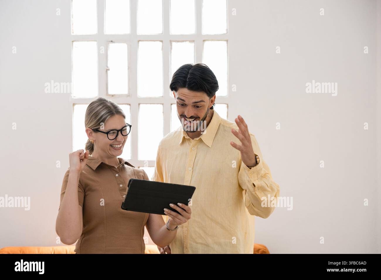 Zufriedene Geschäftspartner feiern Erfolg und schauen auf Tablet Stockfoto