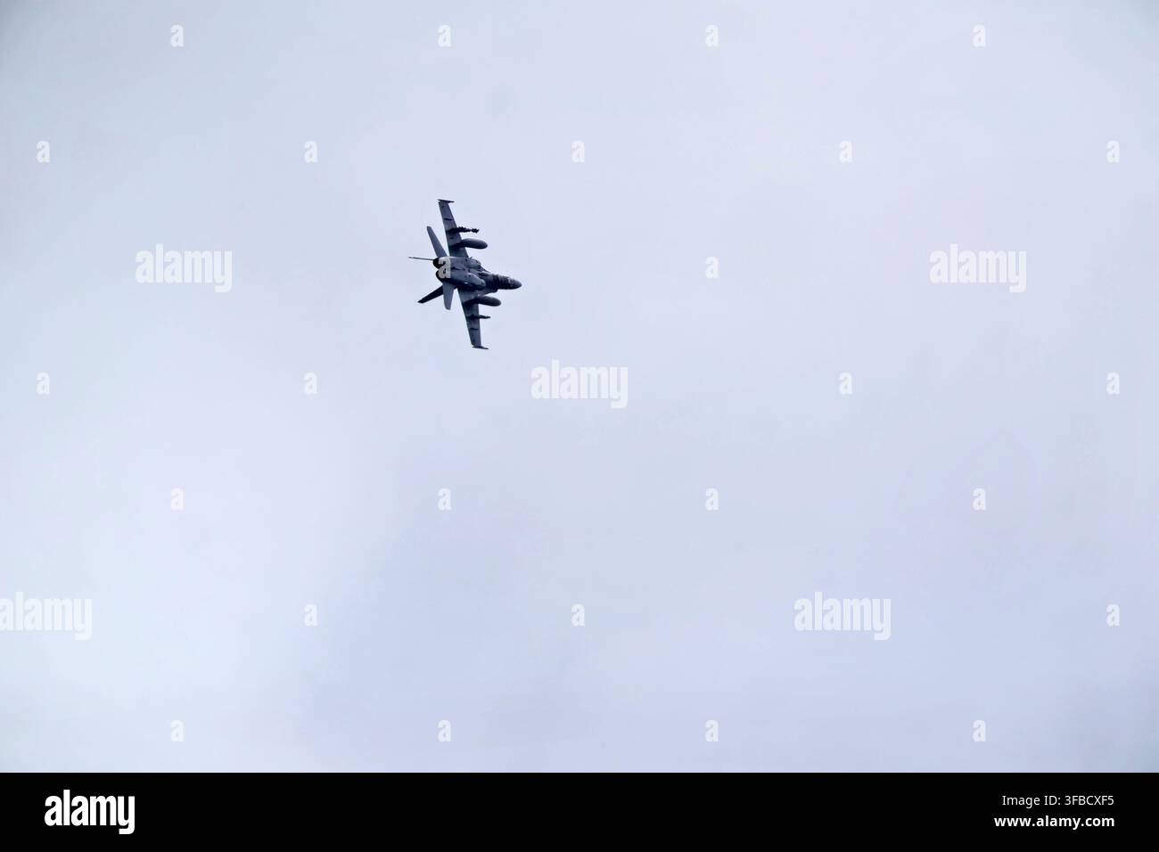 Militärflugzeug führt eine Flugmanöver in bewölktem Himmel durch. Stockfoto