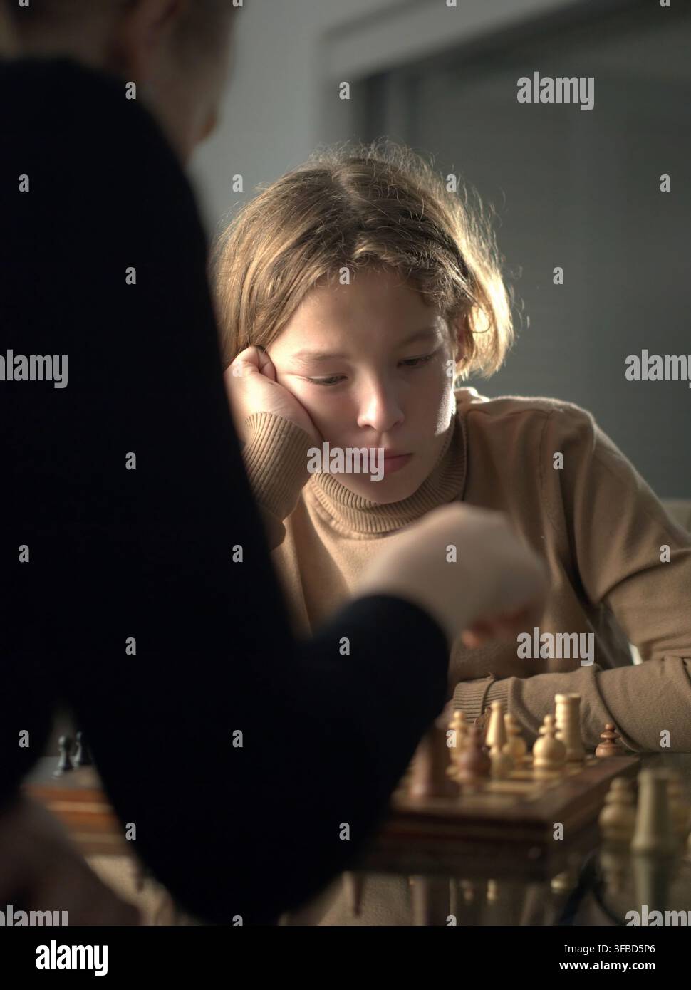 Teenager, der seinen Kopf auf seine Hand stützt, während er Schach spielt Stockfoto