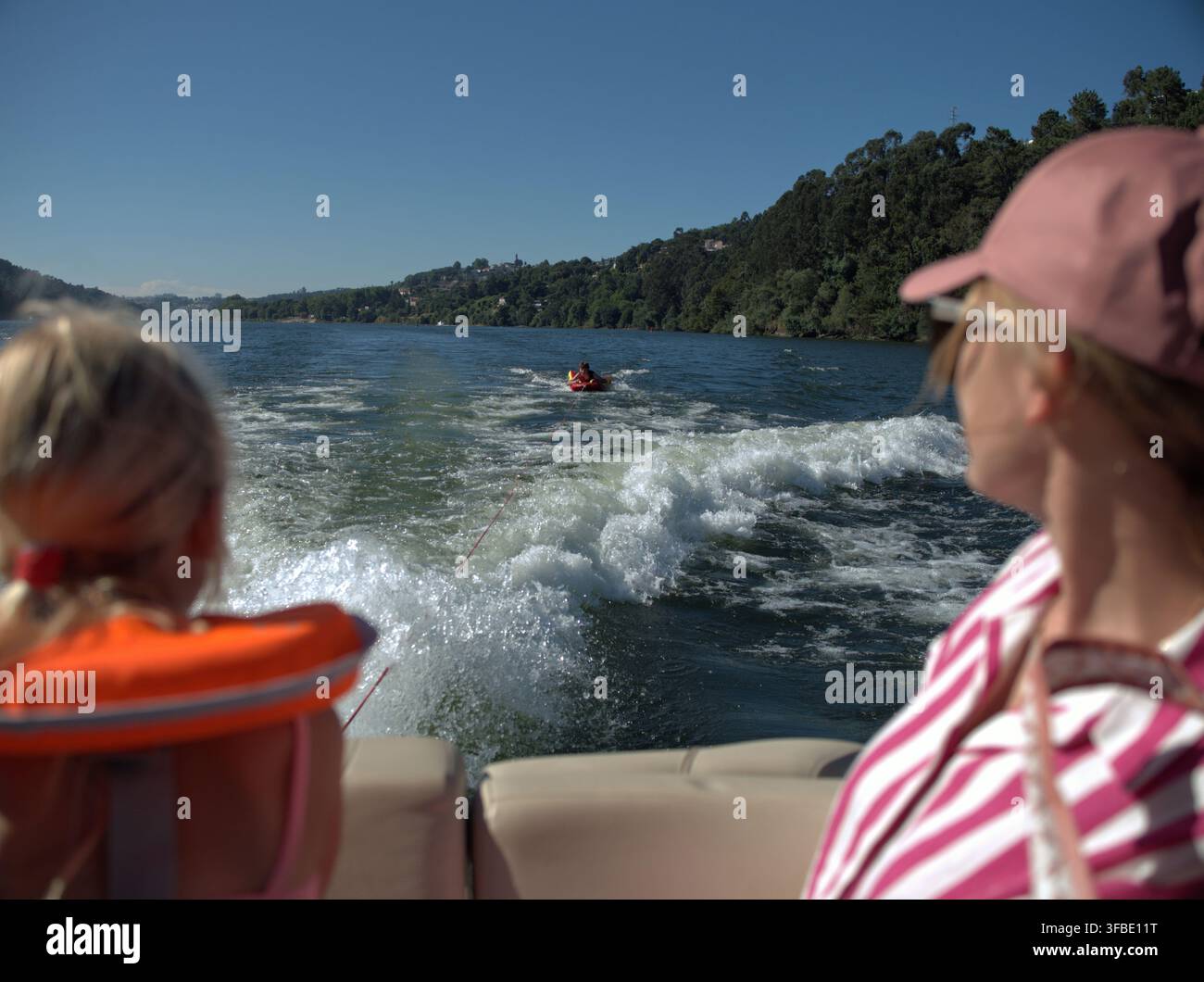 Frau mit einer rosa Kappe beobachtet die Bootswelle Stockfoto