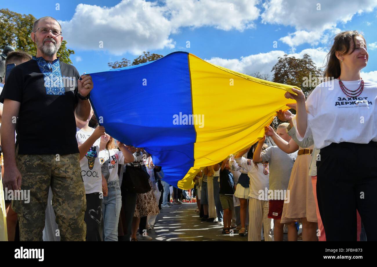 Ukrainer halten eine 35 Meter lange Nationalflagge während einer öffentlichen Veranstaltung zur Feier des Nationalflaggentages in Lemberg, Westukraine, am 23. August 2026. Der Nationalflaggentag wird jährlich in der Ukraine am 23. August begangen, um eines der wichtigsten Staatssymbole des Landes zu ehren. Stockfoto