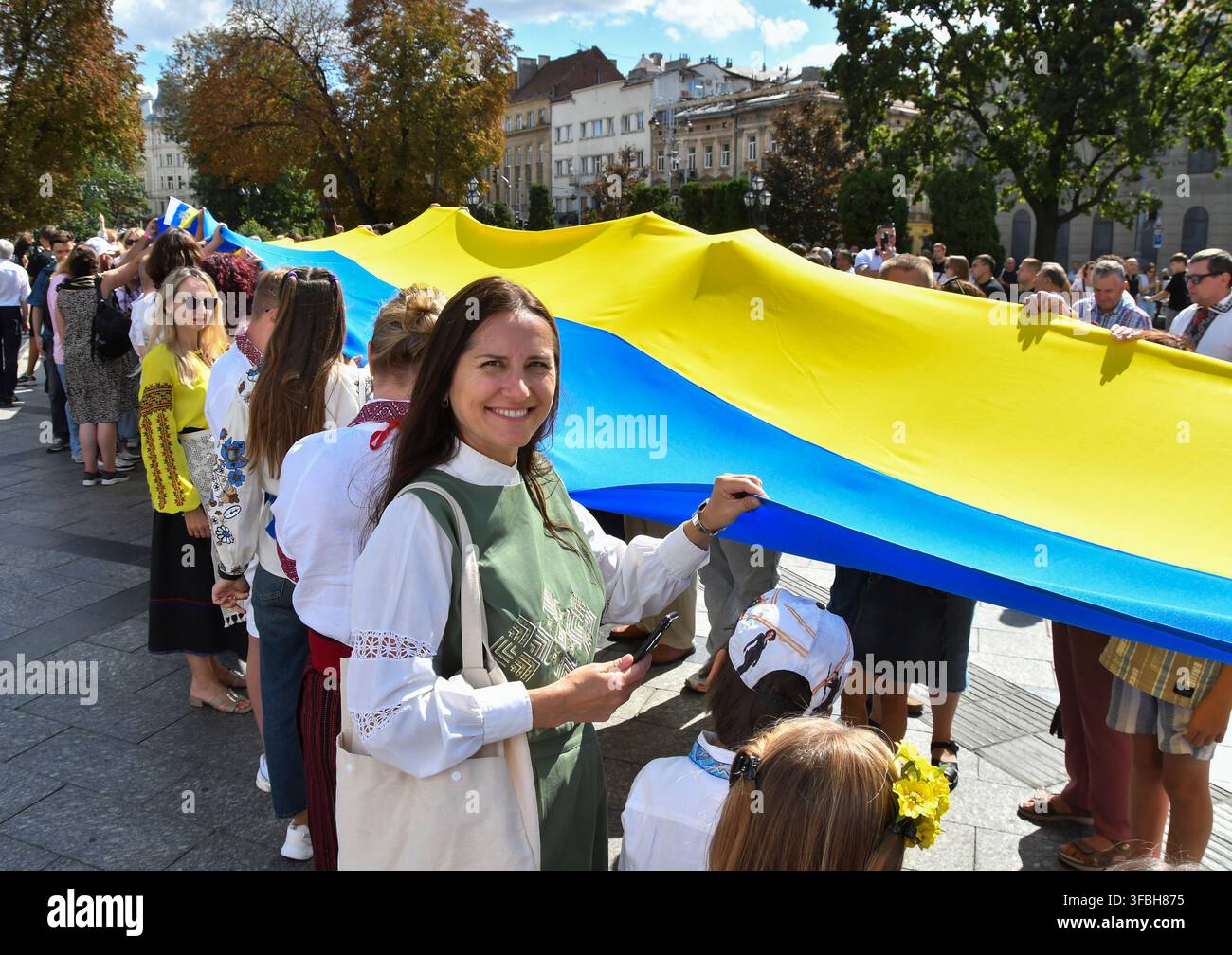 Ukrainer halten eine 35 Meter lange Nationalflagge während einer öffentlichen Veranstaltung zur Feier des Nationalflaggentages in Lemberg, Westukraine, am 23. August 2026. Der Nationalflaggentag wird jährlich in der Ukraine am 23. August begangen, um eines der wichtigsten Staatssymbole des Landes zu ehren. Stockfoto