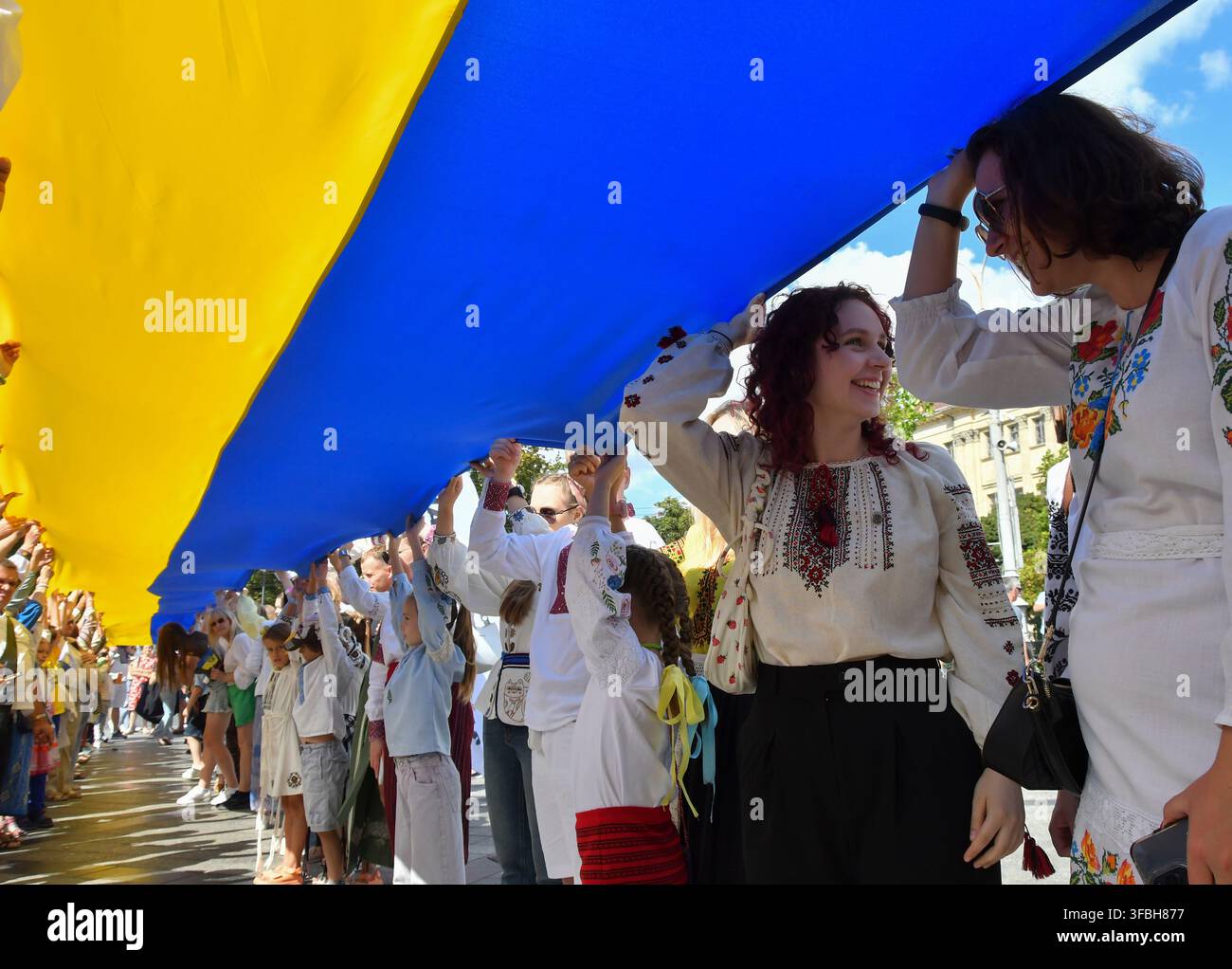 Ukrainer halten eine 35 Meter lange Nationalflagge während einer öffentlichen Veranstaltung zur Feier des Nationalflaggentages in Lemberg, Westukraine, am 23. August 2026. Der Nationalflaggentag wird jährlich in der Ukraine am 23. August begangen, um eines der wichtigsten Staatssymbole des Landes zu ehren. Stockfoto