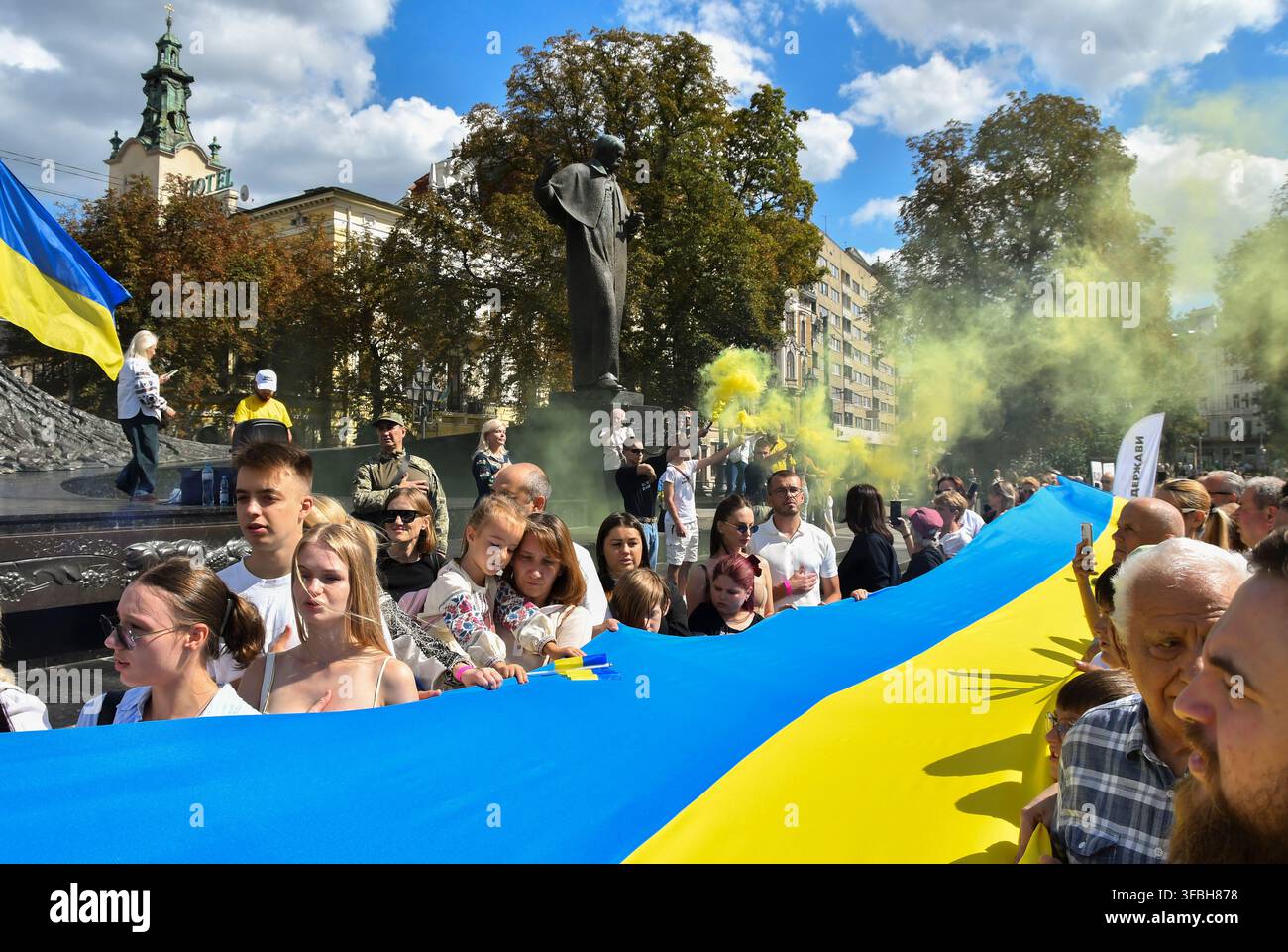 Ukrainer halten eine 35 Meter lange Nationalflagge während einer öffentlichen Veranstaltung zur Feier des Nationalflaggentages in Lemberg, Westukraine, am 23. August 2026. Der Nationalflaggentag wird jährlich in der Ukraine am 23. August begangen, um eines der wichtigsten Staatssymbole des Landes zu ehren. Stockfoto