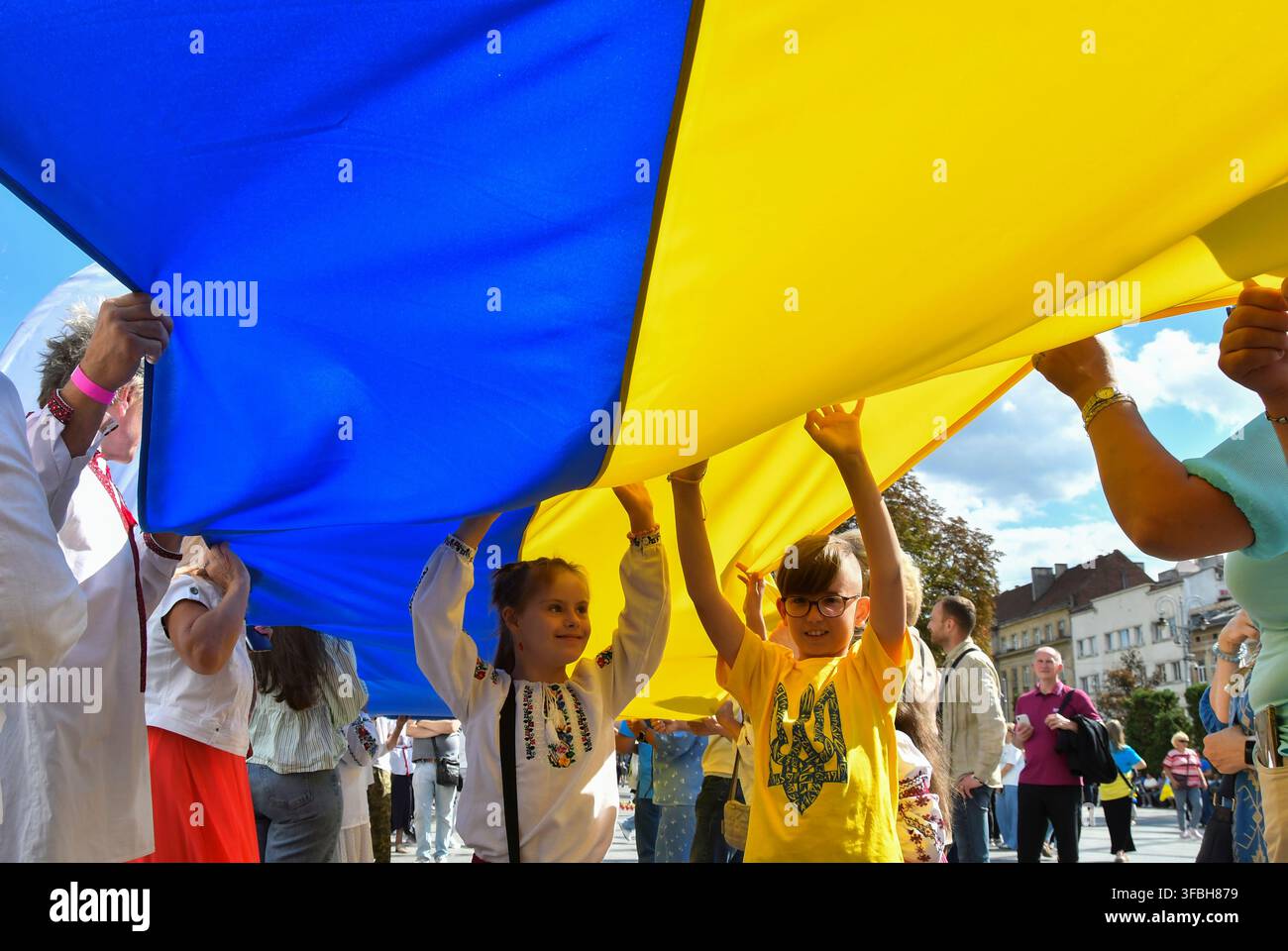 Ukrainer halten eine 35 Meter lange Nationalflagge während einer öffentlichen Veranstaltung zur Feier des Nationalflaggentages in Lemberg, Westukraine, am 23. August 2026. Der Nationalflaggentag wird jährlich in der Ukraine am 23. August begangen, um eines der wichtigsten Staatssymbole des Landes zu ehren. Stockfoto