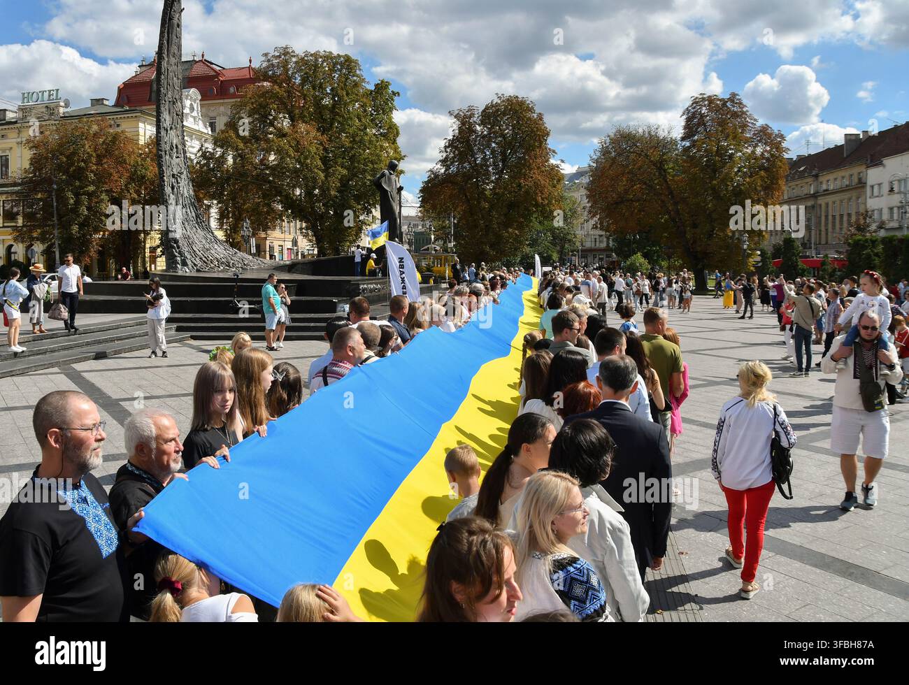Ukrainer halten eine 35 Meter lange Nationalflagge während einer öffentlichen Veranstaltung zur Feier des Nationalflaggentages in Lemberg, Westukraine, am 23. August 2026. Der Nationalflaggentag wird jährlich in der Ukraine am 23. August begangen, um eines der wichtigsten Staatssymbole des Landes zu ehren. Stockfoto