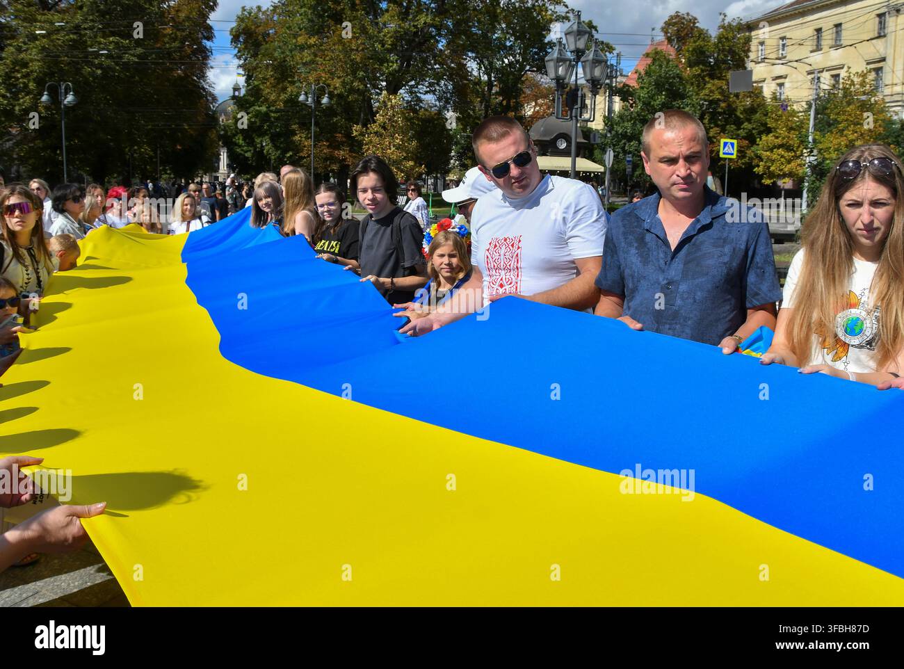 Ukrainer halten eine 35 Meter lange Nationalflagge während einer öffentlichen Veranstaltung zur Feier des Nationalflaggentages in Lemberg, Westukraine, am 23. August 2026. Der Nationalflaggentag wird jährlich in der Ukraine am 23. August begangen, um eines der wichtigsten Staatssymbole des Landes zu ehren. Stockfoto