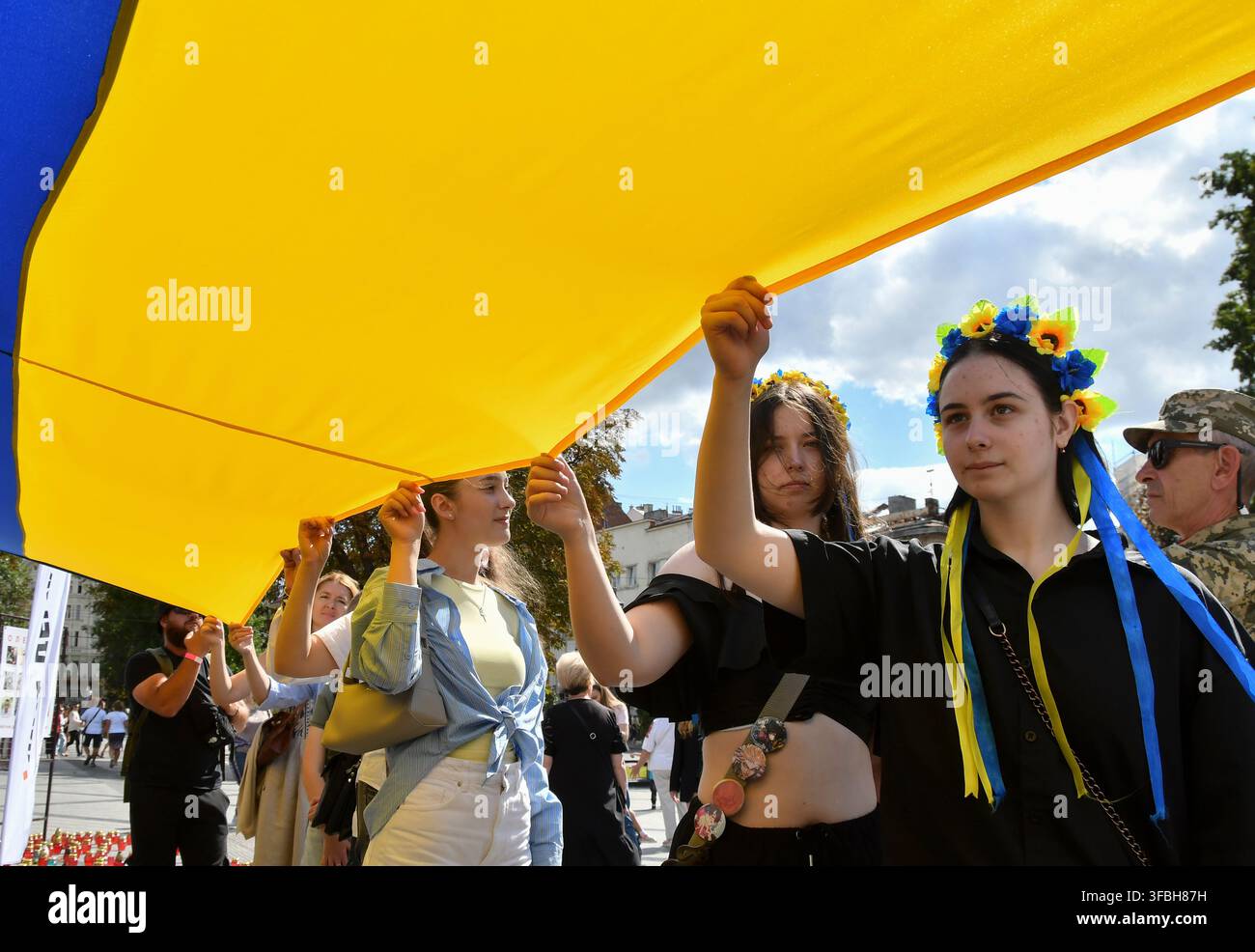 Ukrainer halten eine 35 Meter lange Nationalflagge während einer öffentlichen Veranstaltung zur Feier des Nationalflaggentages in Lemberg, Westukraine, am 23. August 2026. Der Nationalflaggentag wird jährlich in der Ukraine am 23. August begangen, um eines der wichtigsten Staatssymbole des Landes zu ehren. Stockfoto