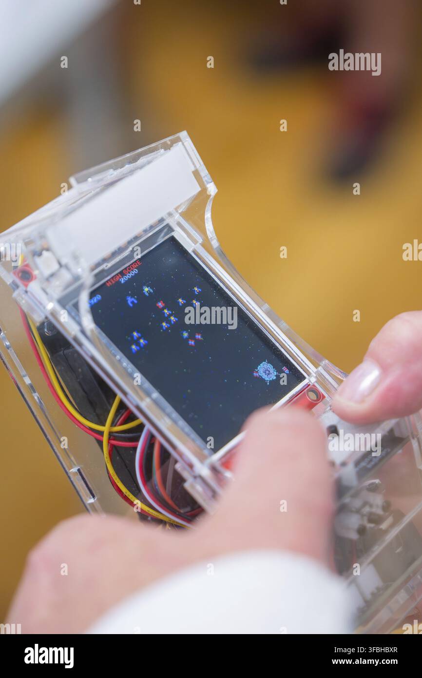 Eine Person hält eine transparente Handheld-Konsole mit einem laufenden Arcade-Spiel, Jugendforschungszentrum, Nagold, Deutschland Stockfoto