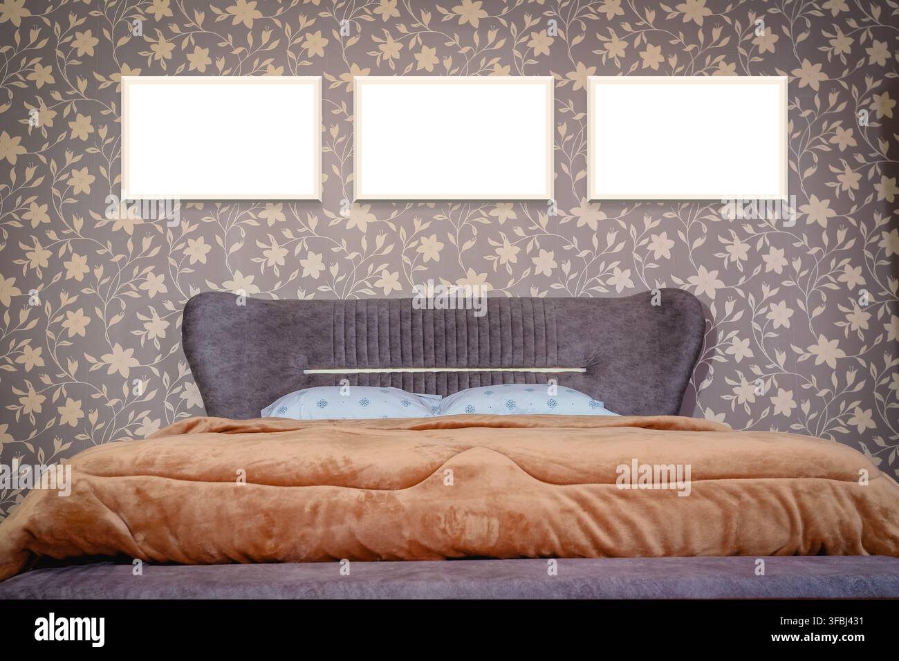 Drei leere Rahmen über einem modernen Schlafzimmerbett Stockfoto