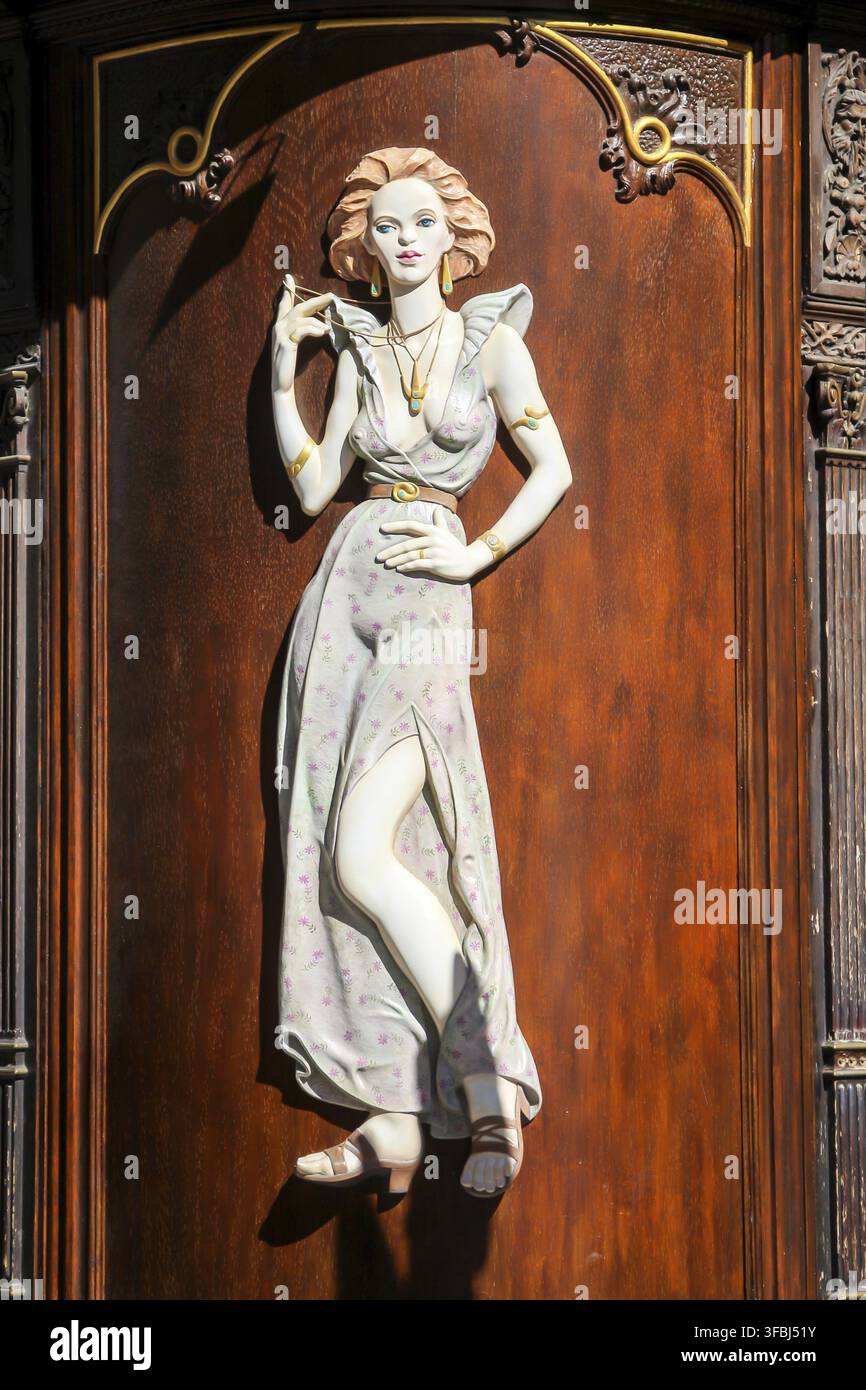 Eine weiße Holzfigur an einer rötlichen Holzwand Stockfoto