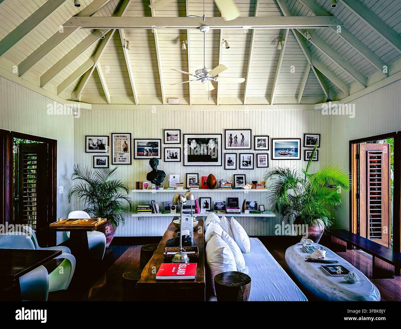 Inneneinrichtung des Fleming-Raums im GoldenEye-Resort, Jamaika, mit gerahmten Fotografien, Ian-Fleming-Andenken, Büchern, tropischen Pflanzen, Deckenventilatoren Stockfoto