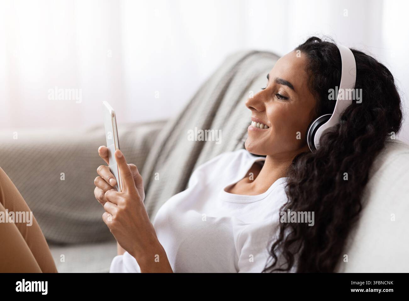 Glückliche junge Frau in Kopfhörer mit Handy Stockfoto