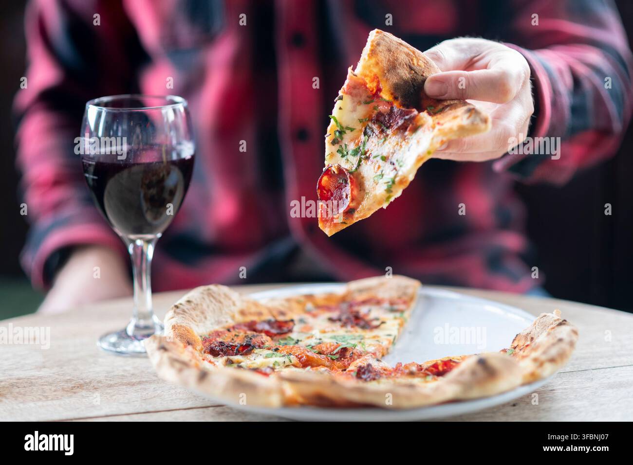 Leckere Pizza und Wein schaffen einen perfekten Essmoment in gemütlicher Atmosphäre Stockfoto