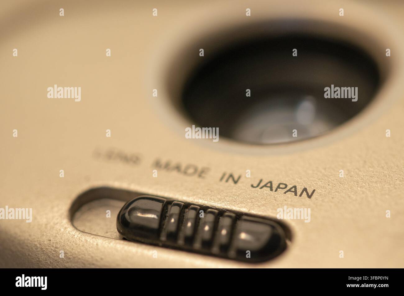 Objektiv hergestellt in Japan, Schrift und Plastikknopf auf billiger Einwegfilmkamera Stockfoto